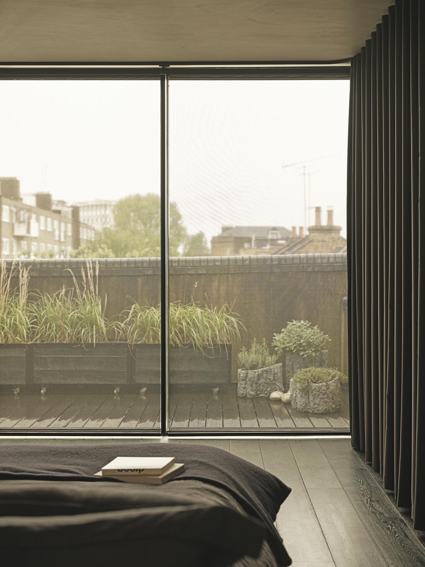 Große Fensterfront mit transparentem Vorhang und dunklem Textilrahmen im Schlafraum