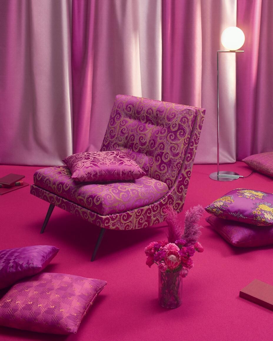 Polstersessel mit violettem Ornamentstoff, Kissen und Vorhänge im Farbraum