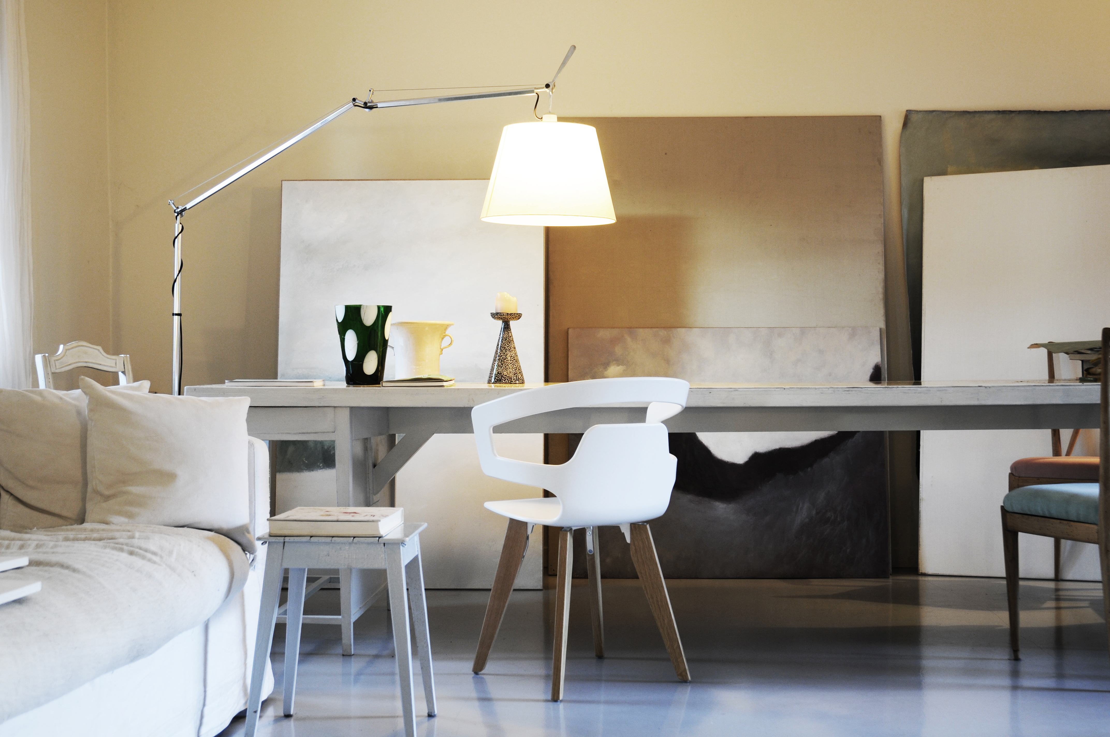 Raum mit modernem Tisch, weißen Stühlen von Alias und großformatigen Leinwänden im Hintergrund