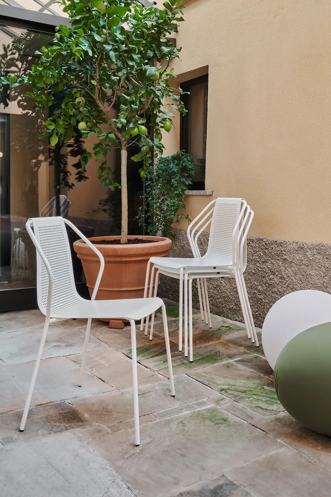 weiße Stühle aus Metall stehen nebeneinander im Innenhof