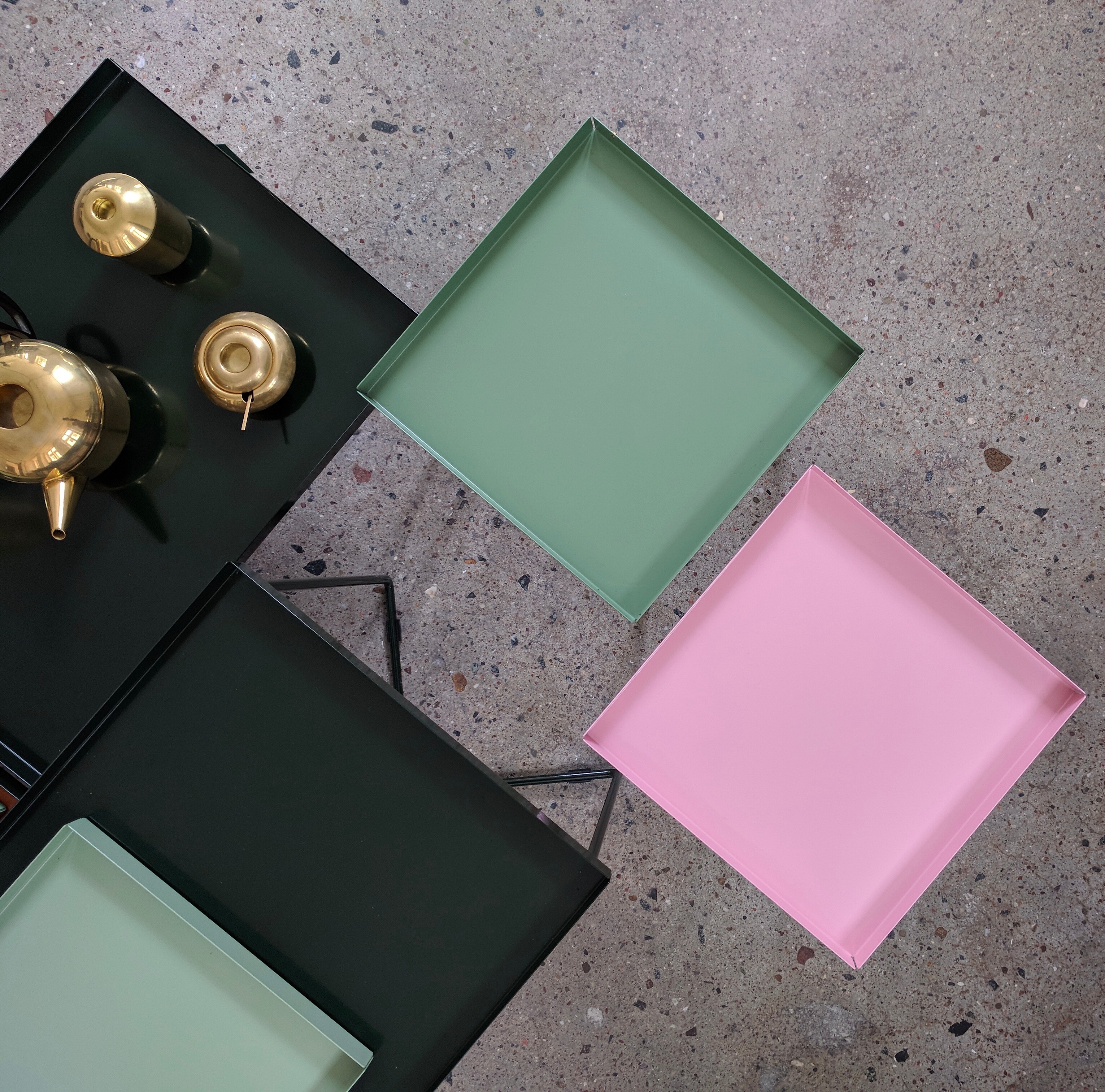 farbige POI-Tabletts auf POI-Beistelltischen auf rauem Betonboden arrangiert