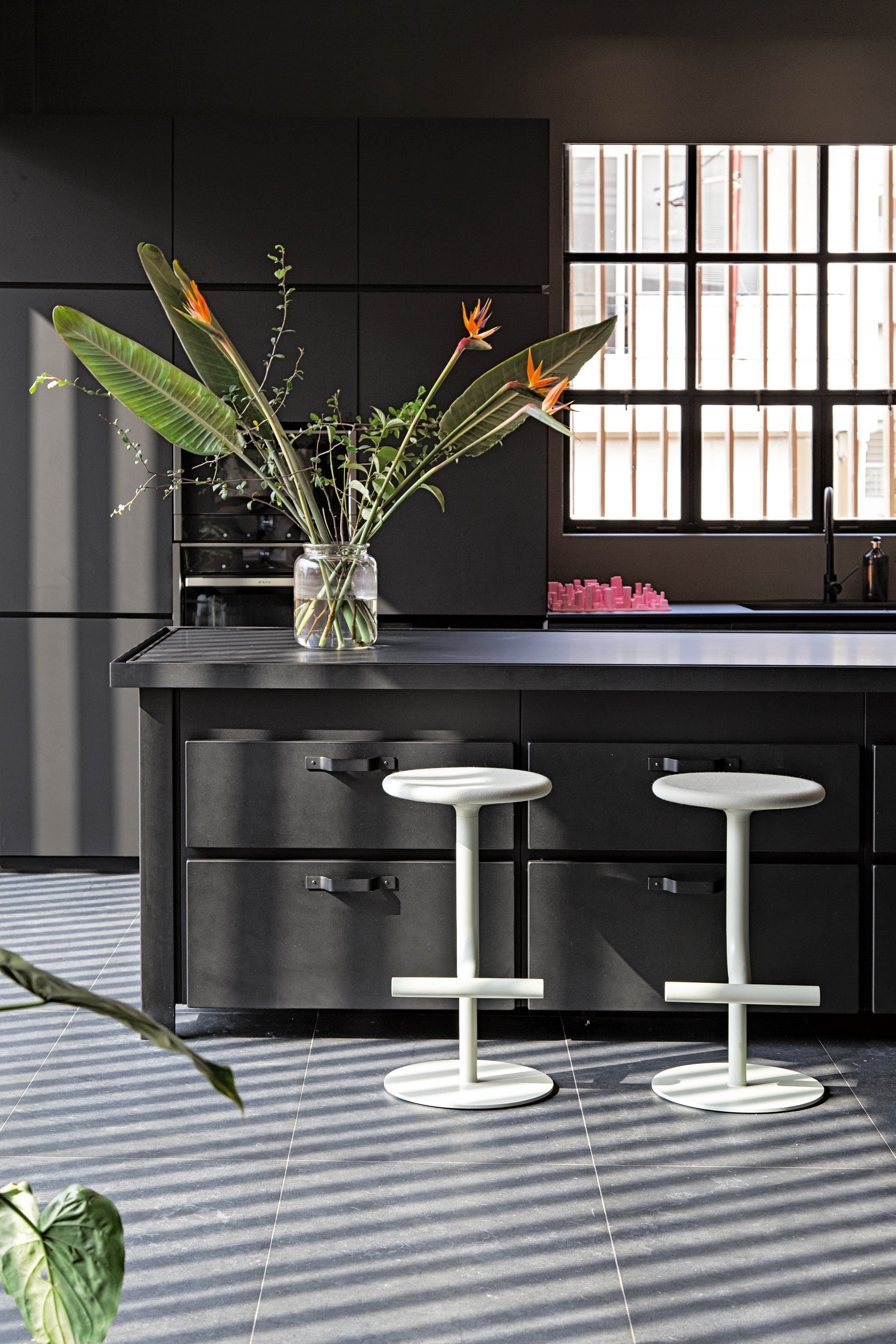 Zwei weiße Tibu Barhocker von Magis an dunkler Kücheninsel mit großer Glasvase