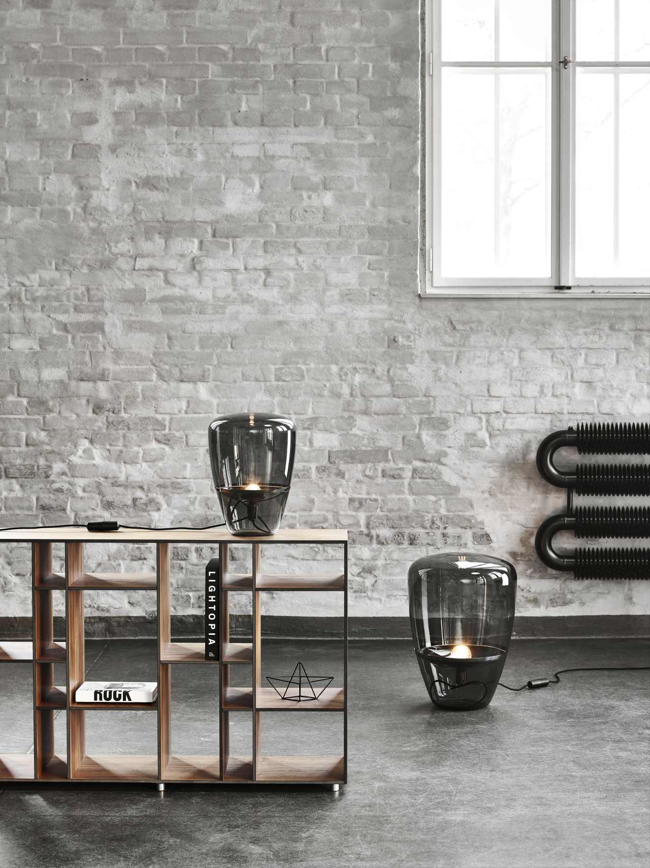 Zwei mundgeblasene Brokis-Leuchten vor Ziegelwand und offenem Regal aus Holz