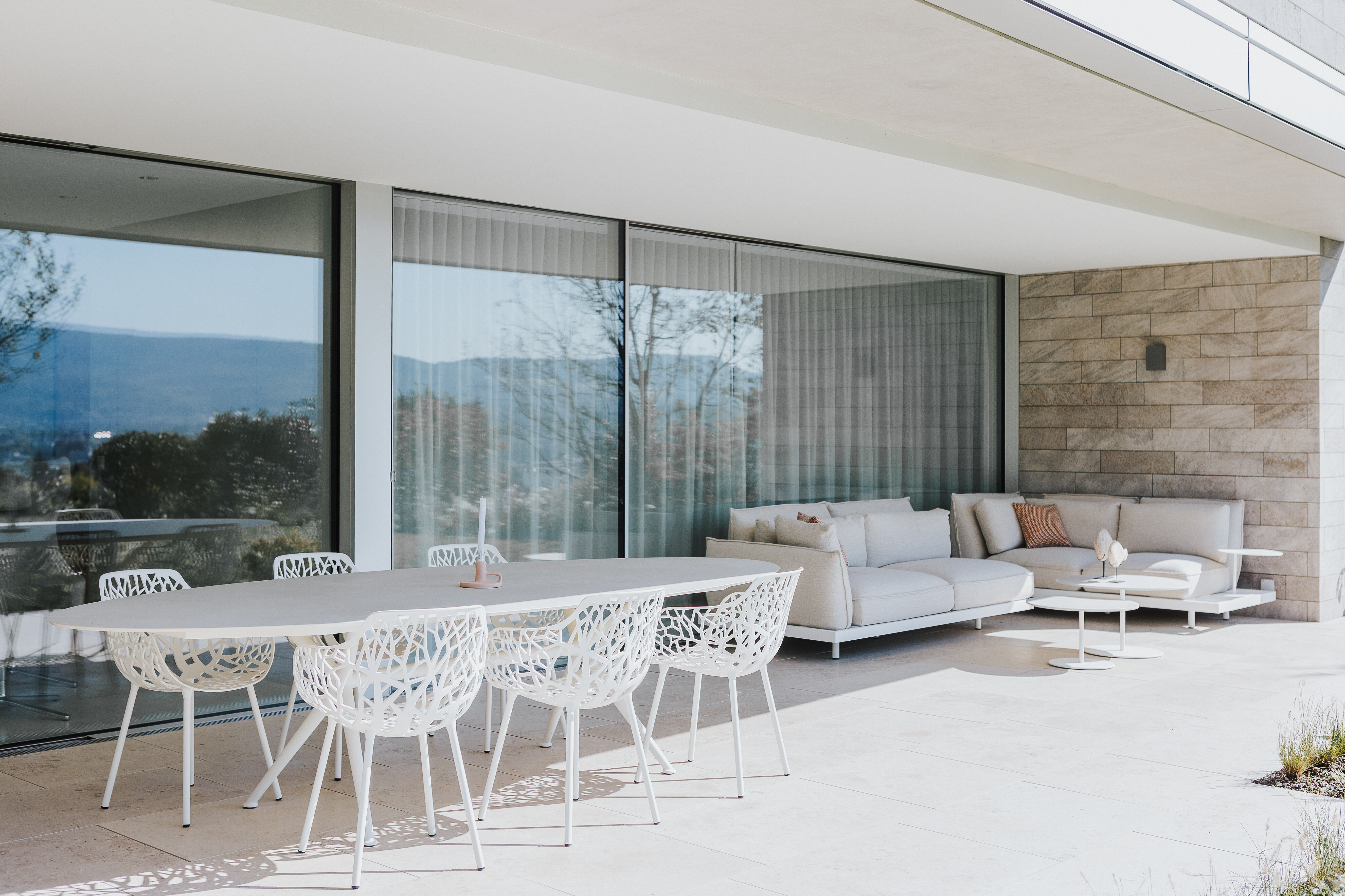 Terrasse mit weißem Esstisch und Lounge in hellen Tönen – Einrichtungskonzept von Seipp Wohnen.