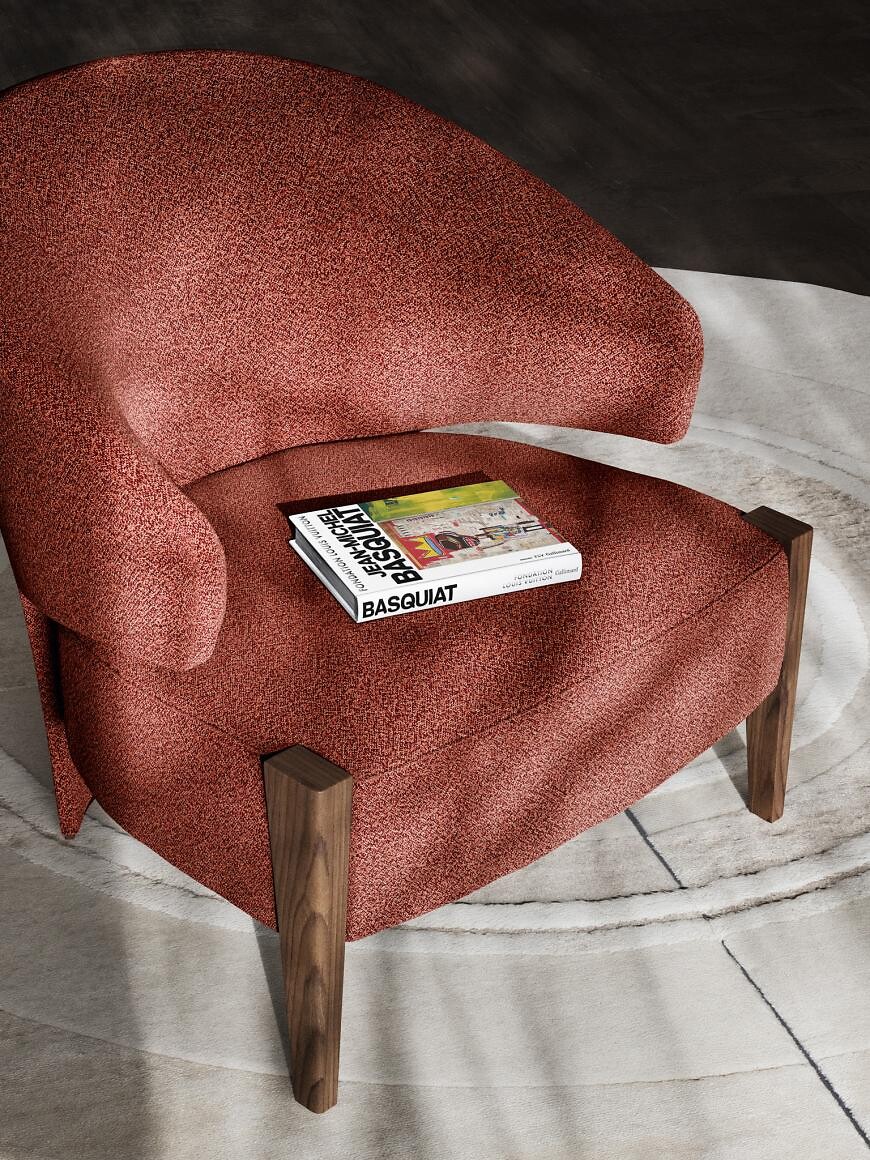 Sessel in rostrotem Stoffbezug mit organischer Form und Holzfüßen auf hellem Teppich