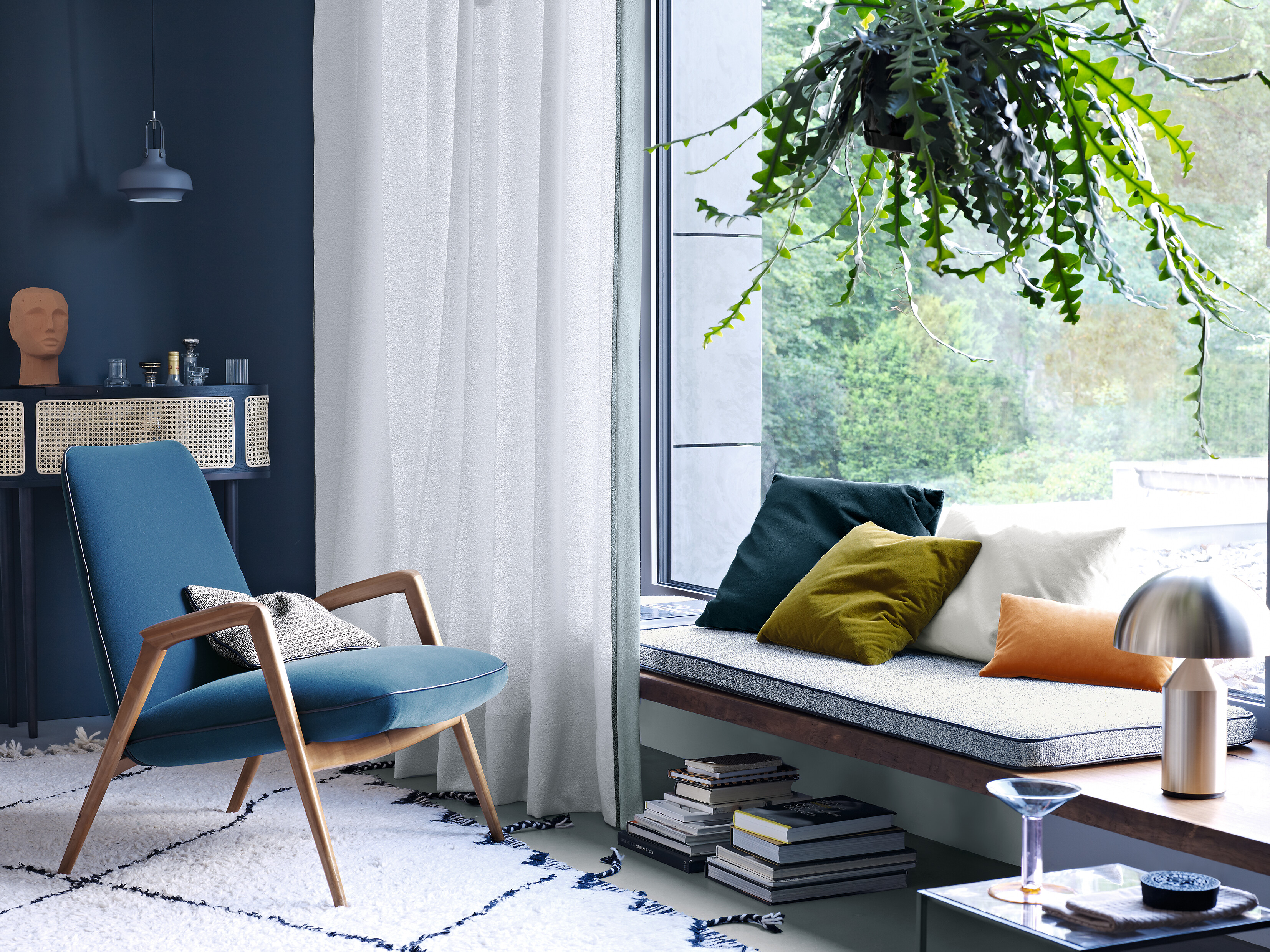 Polsterbank am Fenster mit Kissen in verschiedenen Farben und Texturen