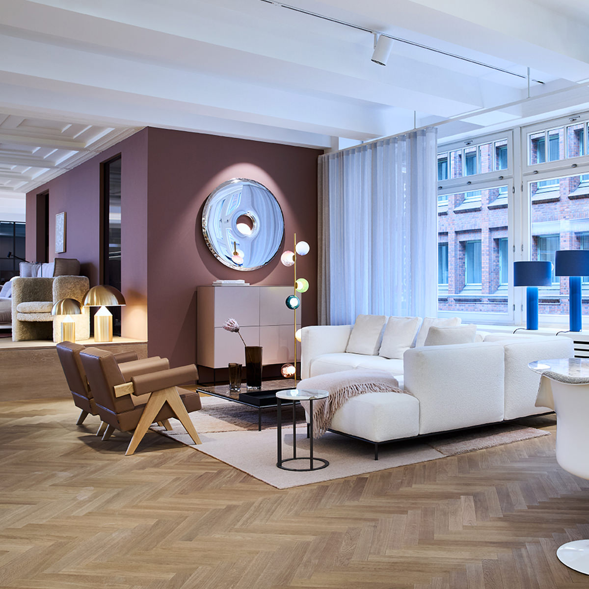 Showroom: stilvolle Wohnlandschaft. Komfortables Mex-Hi Sofa und eleganter Capitol Complex Sessel von Cassina laden ein. Ergänzt durch Zieta Spiegel Rondo, Form1 Sideboard, blaue Victor Foxtrot Tischleuchten.