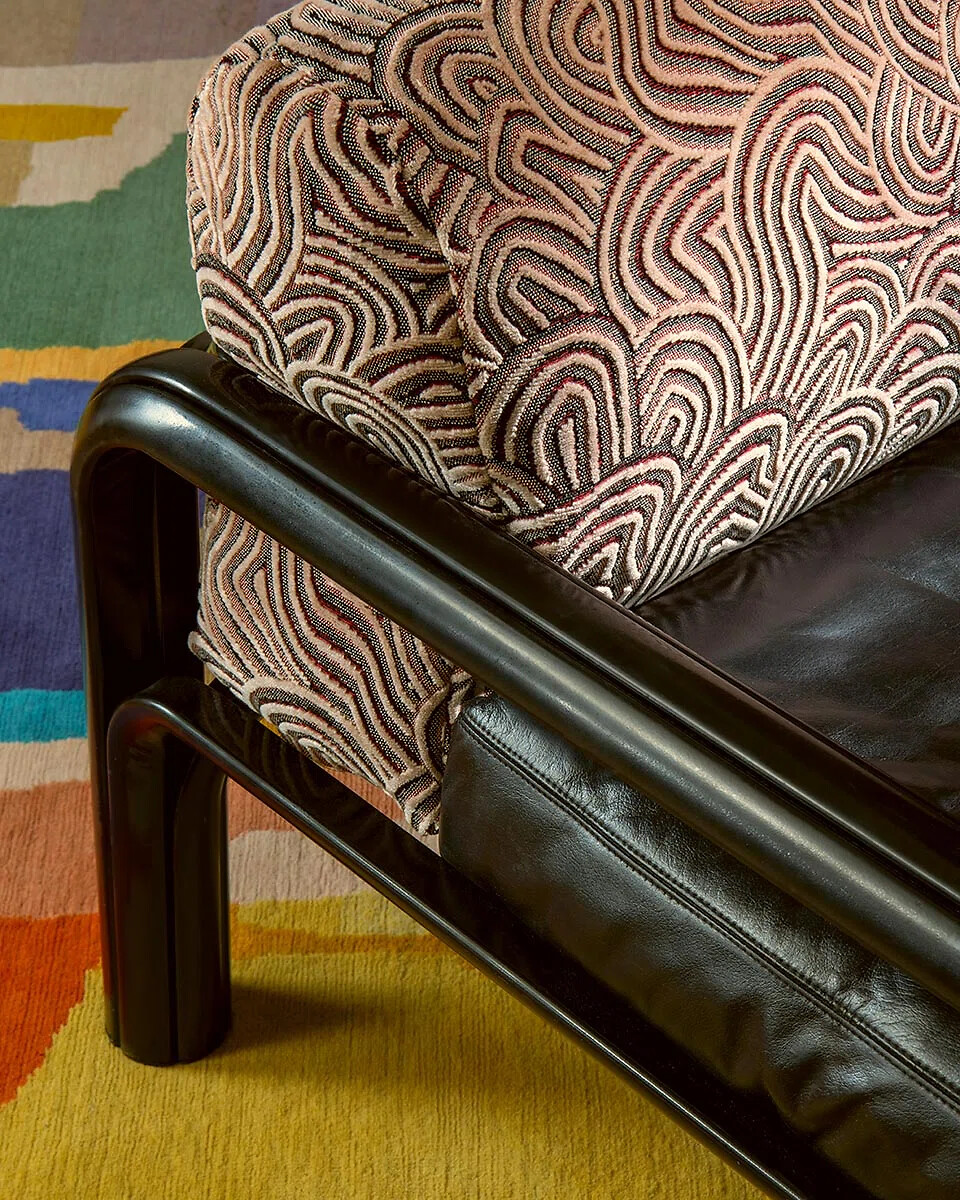 Detailaufnahme eines Sessels mit gemustertem Polsterstoff und Holzrahmen