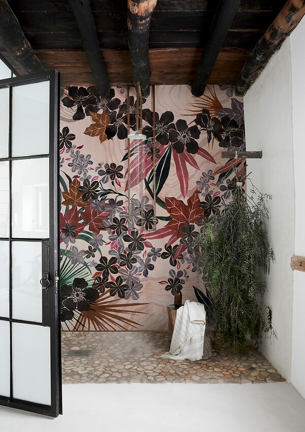 Florale Tapete in warmen Rottönen an einer Wand mit Holzdecke und Natursteinboden