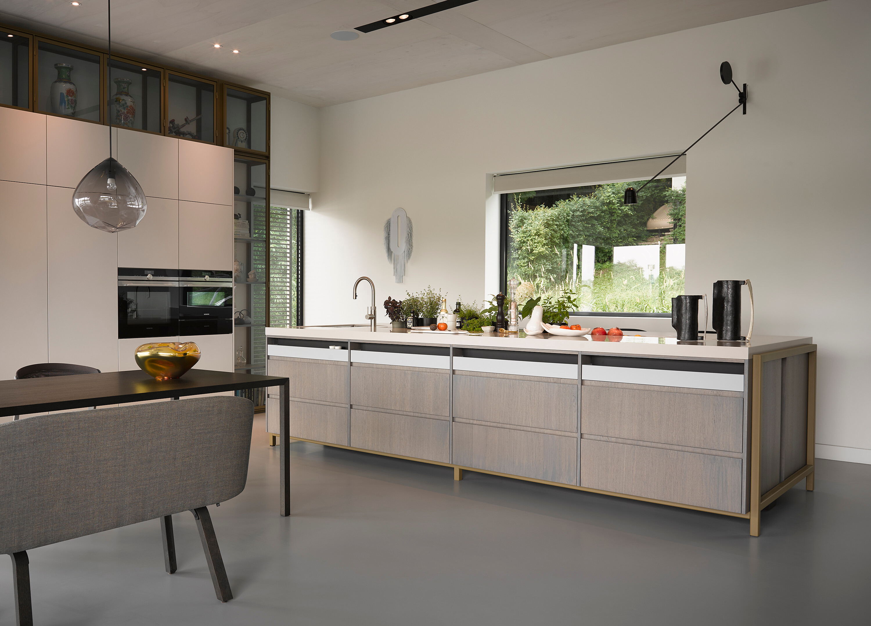 Helle Küche und Esstisch vor Fenster mit Blick ins Grüne