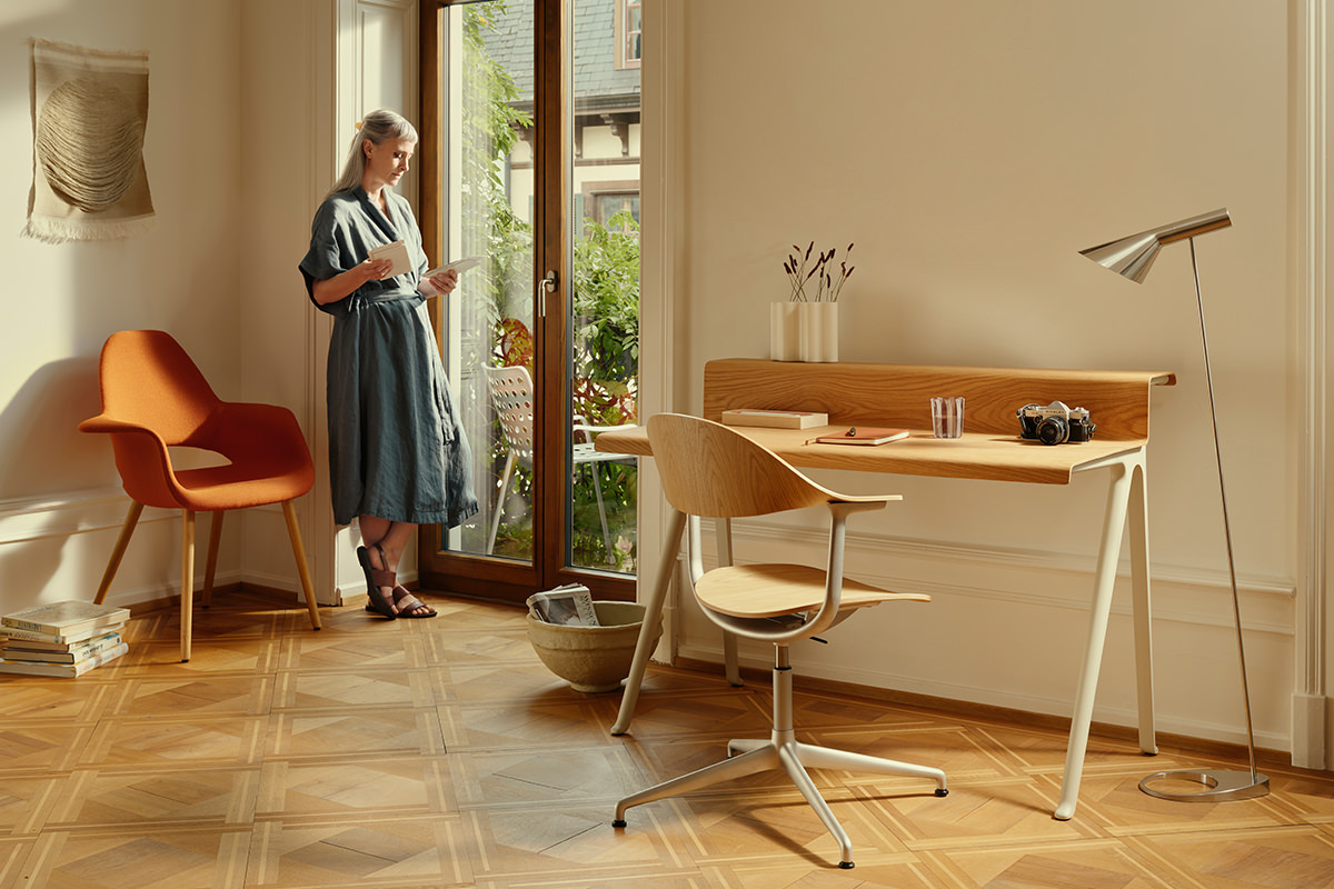 Funktionaler Raum mit Vitra Möbeln: Courier Schreibtisch und Mynt Drehstuhl schaffen modernen Arbeitsplatz. Organic Chair lädt zum Entspannen ein. Nuage Vase und Landi Stuhl am Balkon runden das Ambiente ab.