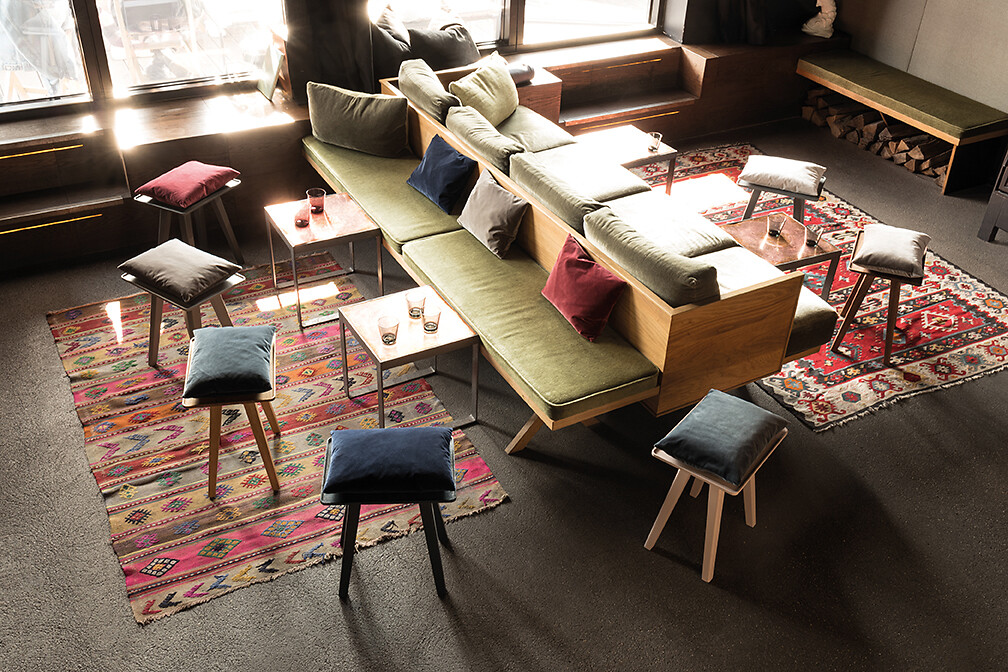 Mehrere Schönbuch Hocker rund um ein Sofaensemble mit farbigen Kissen und Teppichen