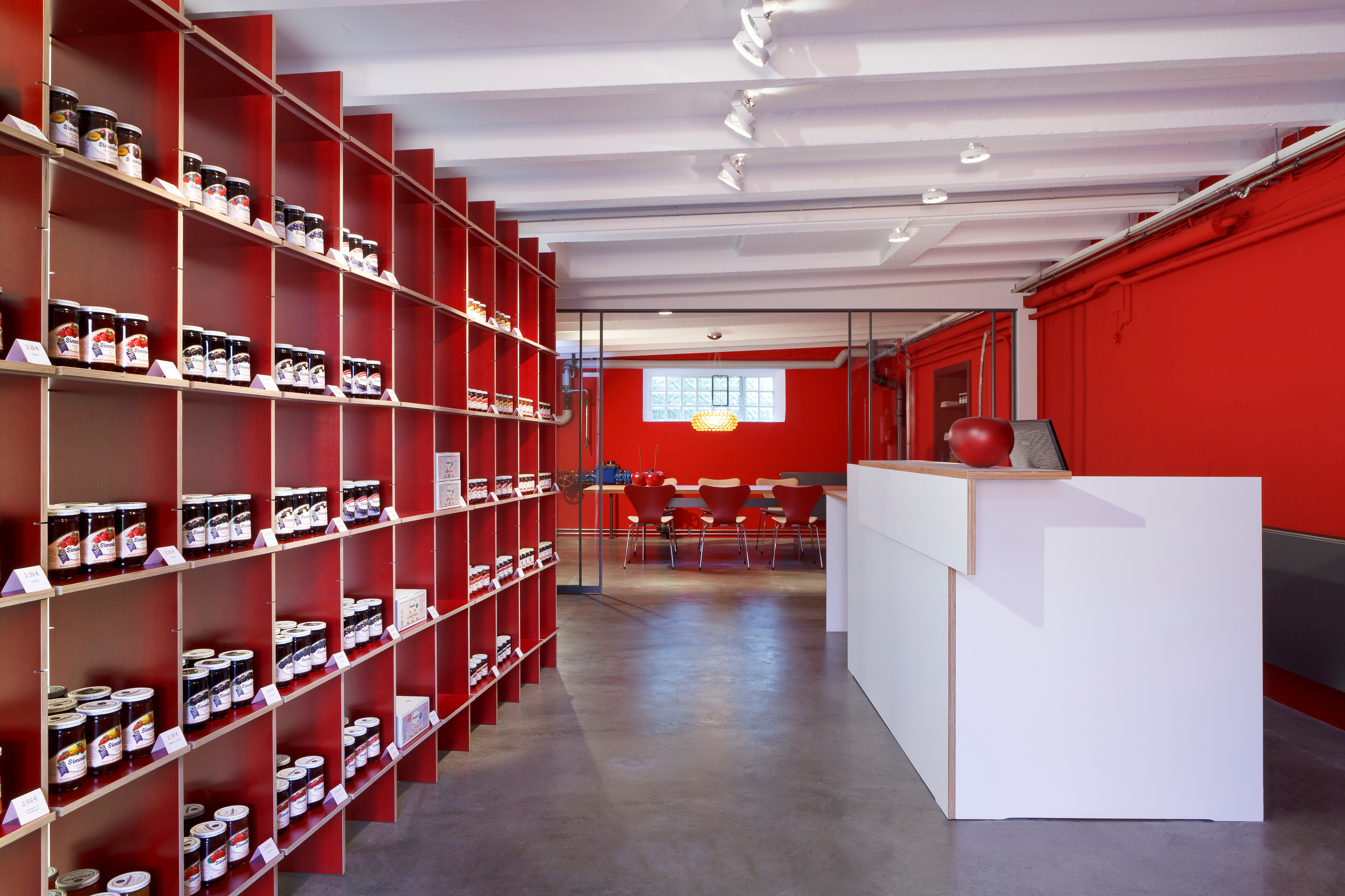 Der Konfitürenspezialist wünschte sich einen Raum für die Warenpräsentation und eine Lösung als Rückzugsort und für ungestörte Besprechungen. Hierfür wurde der als Archiv genutzte Gebäudeteil zwischen Produktion und Verwaltung umgebaut. Der dunkle Ort wur