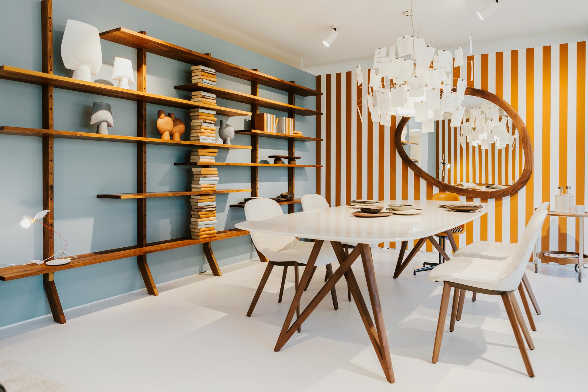 Gestalteter Essbereich im Schaufenster Tiengen mit Zettel’z-Leuchte, Bücherwand und grafischer Kulisse