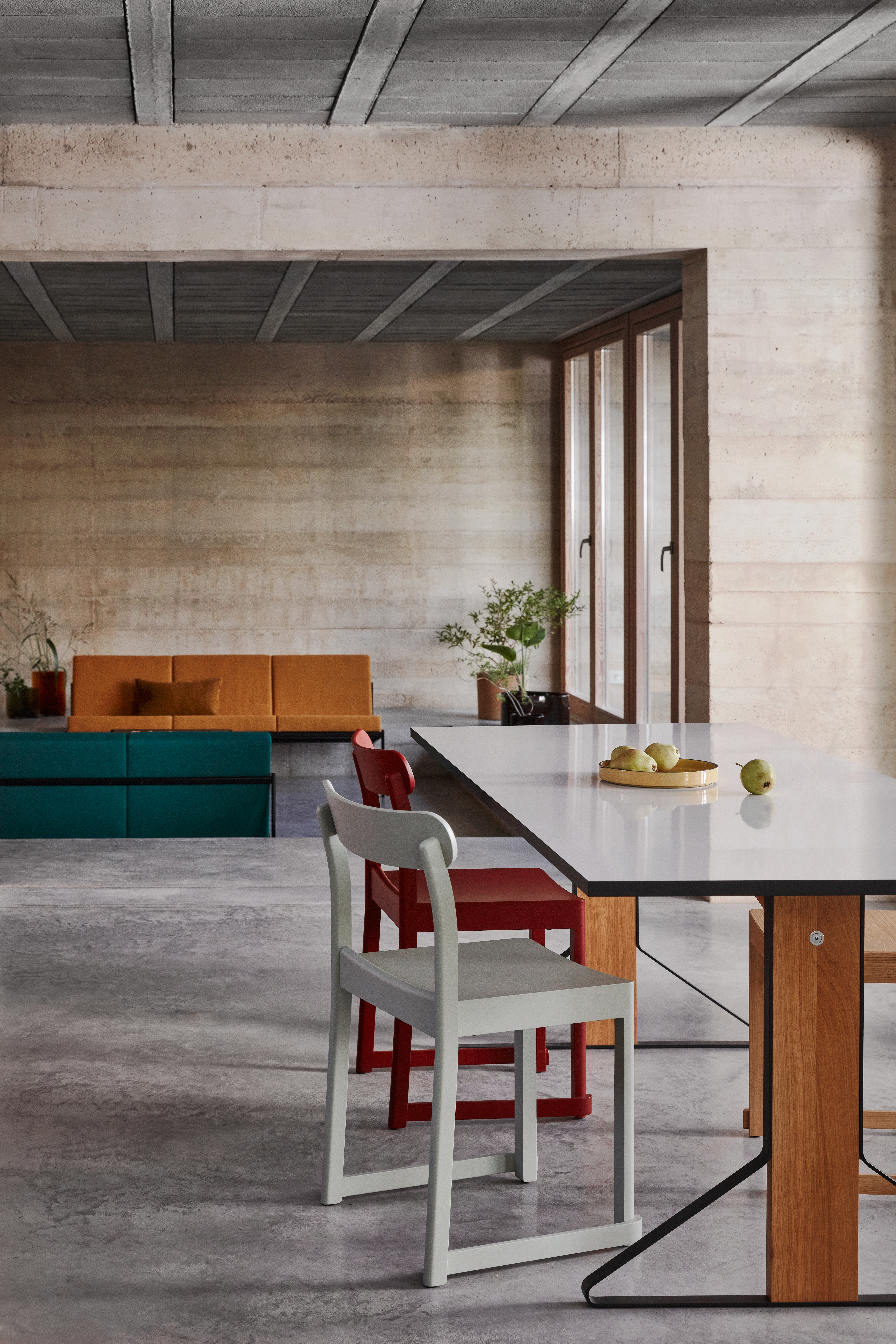 Essbereich mit weißer Tischplatte, Holzdetails und zwei unterschiedlich farbigen Stühlen