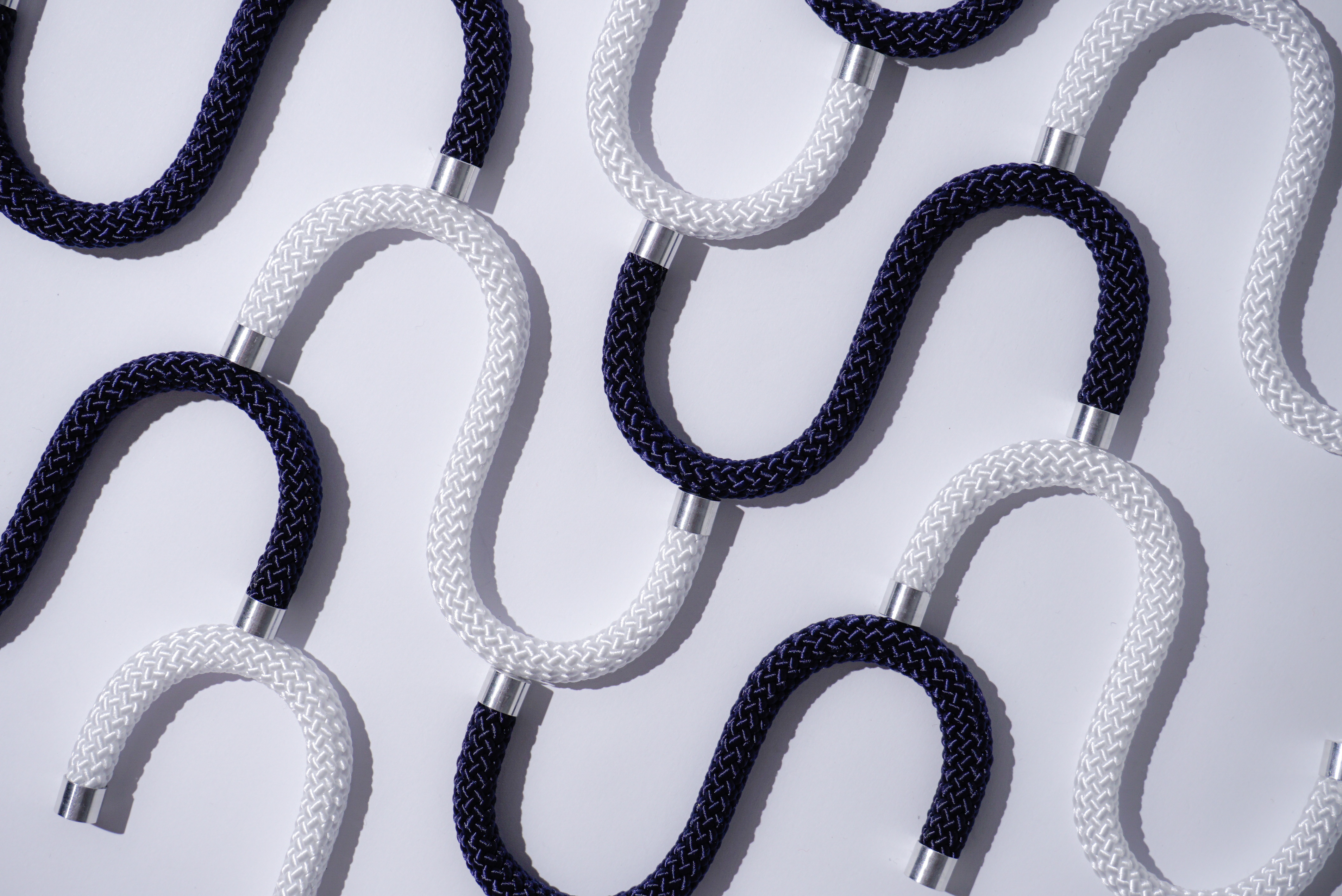 Schwarz-weiße Seilhaken in geschwungener Anordnung auf heller Fläche nebeneinander