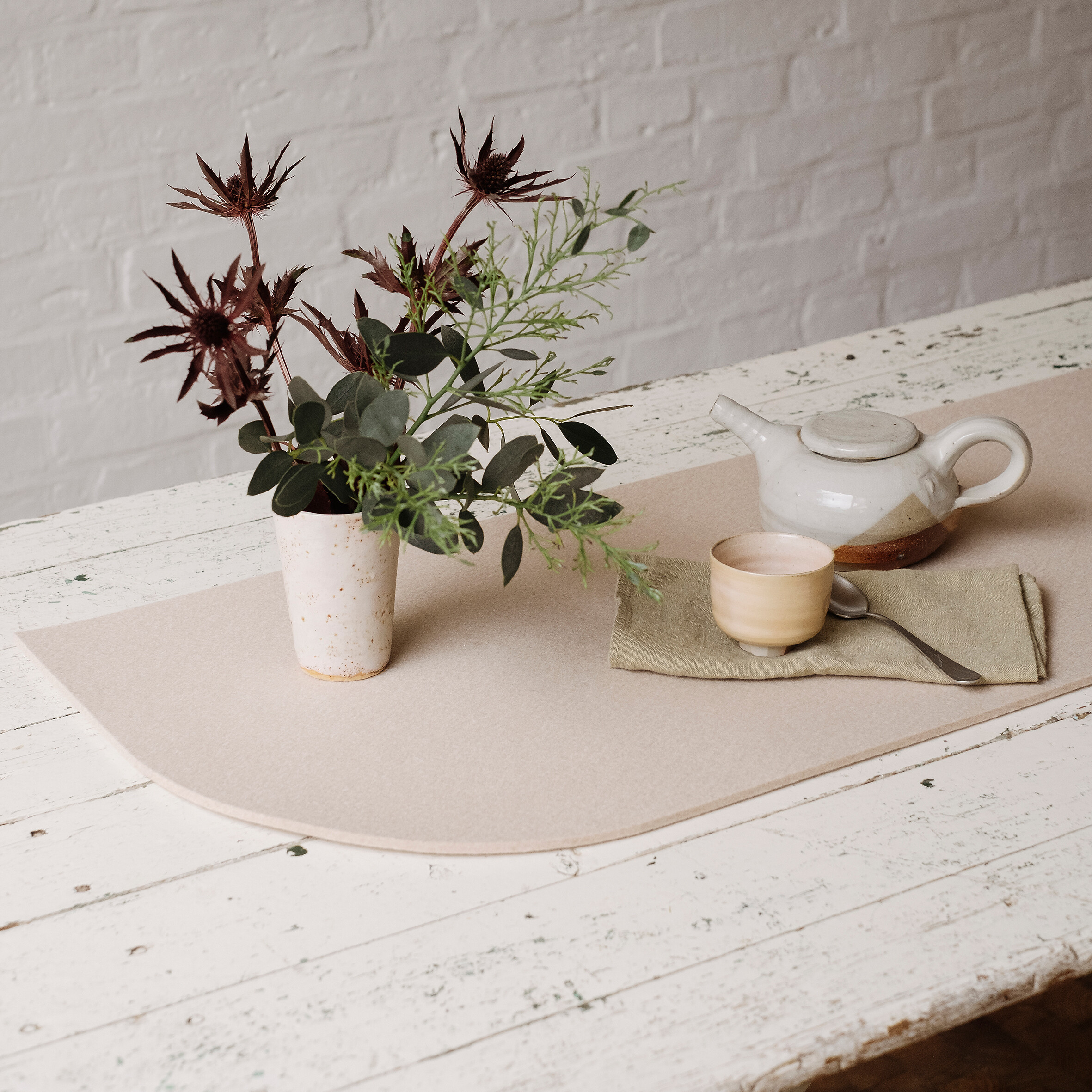 Tischläufer in hellem Beige aus Filz mit Keramik und Blumenarrangement