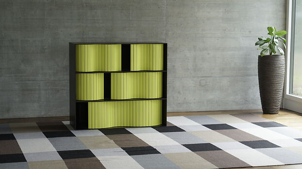 Kommode mit offenen Fächern und grüngelben Lamellenfronten auf Teppichboden