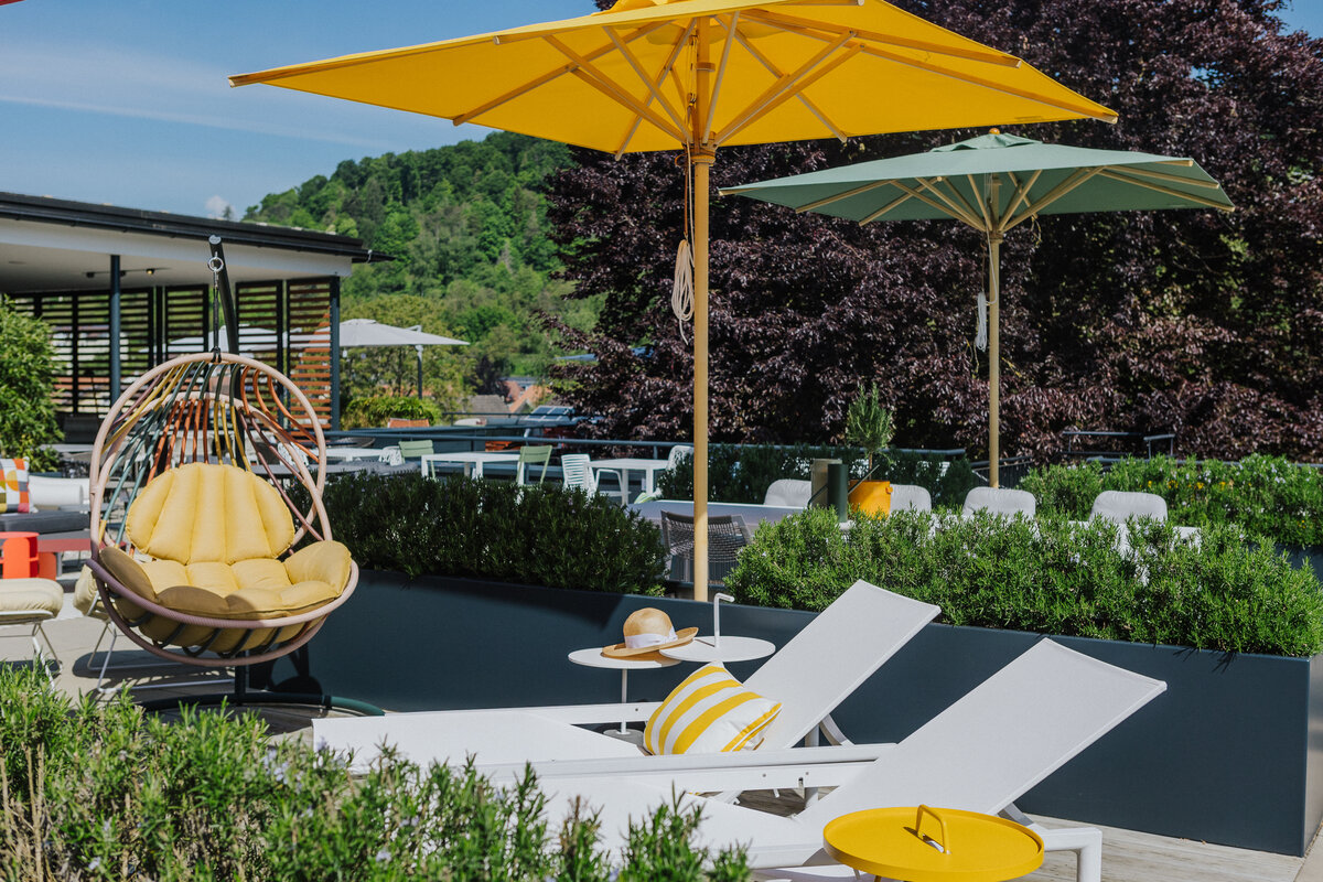 Dachterrasse in Tiengen mit Gartenliegen, gelben Sonnenschirmen und einem Hängesessel in Gelbtönen