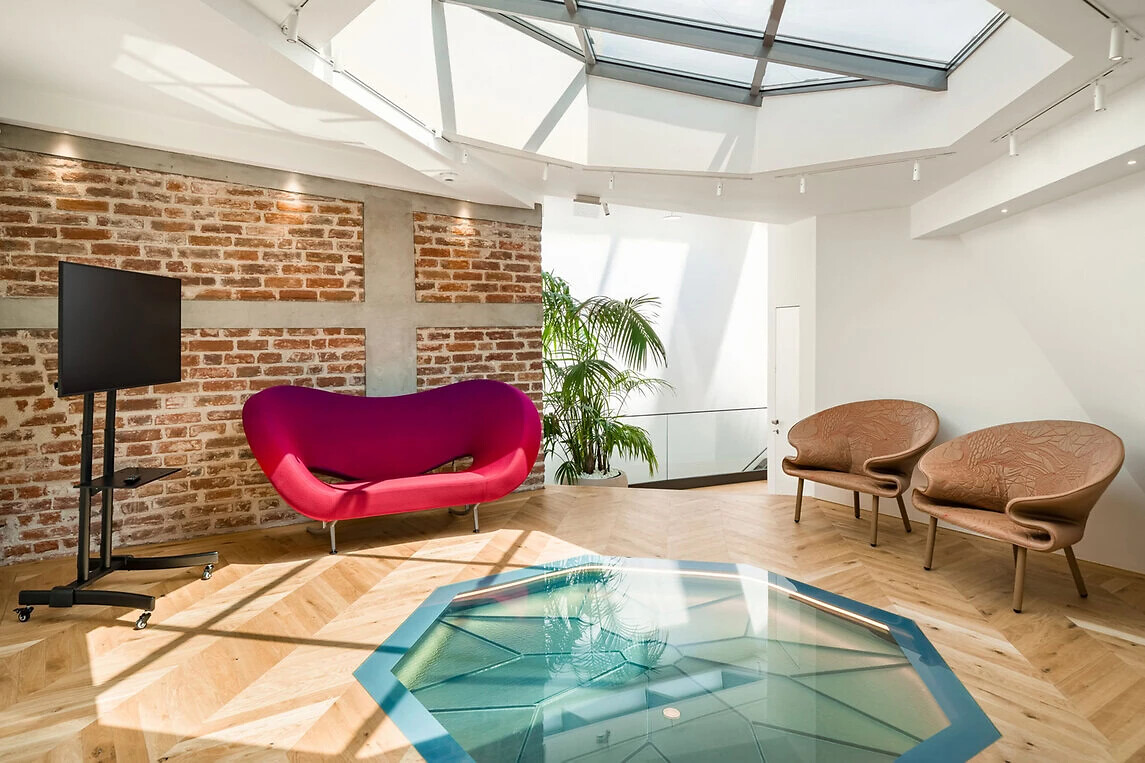 Raum mit roten und bronzefarbenen Sesseln sowie skulpturalem Couchtisch