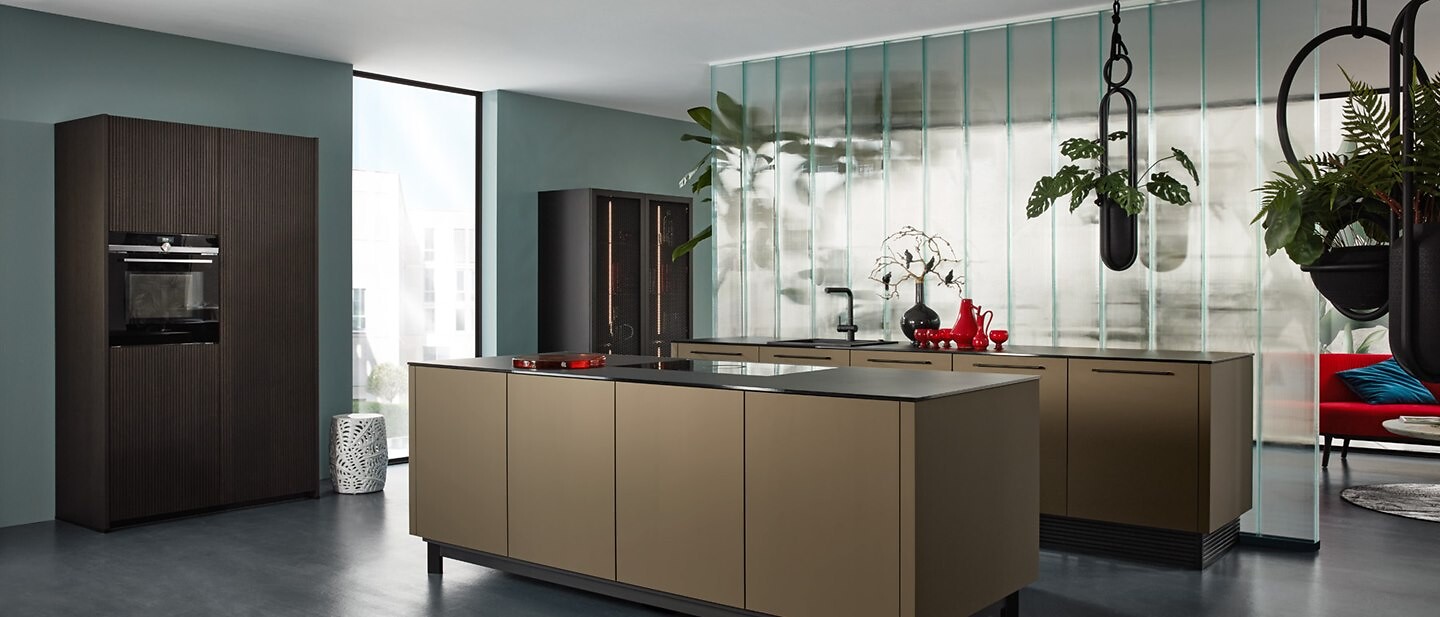 Küche von Nolte mit braungoldenen Fronten, dunklen Hochschränken und großzügiger Insel
