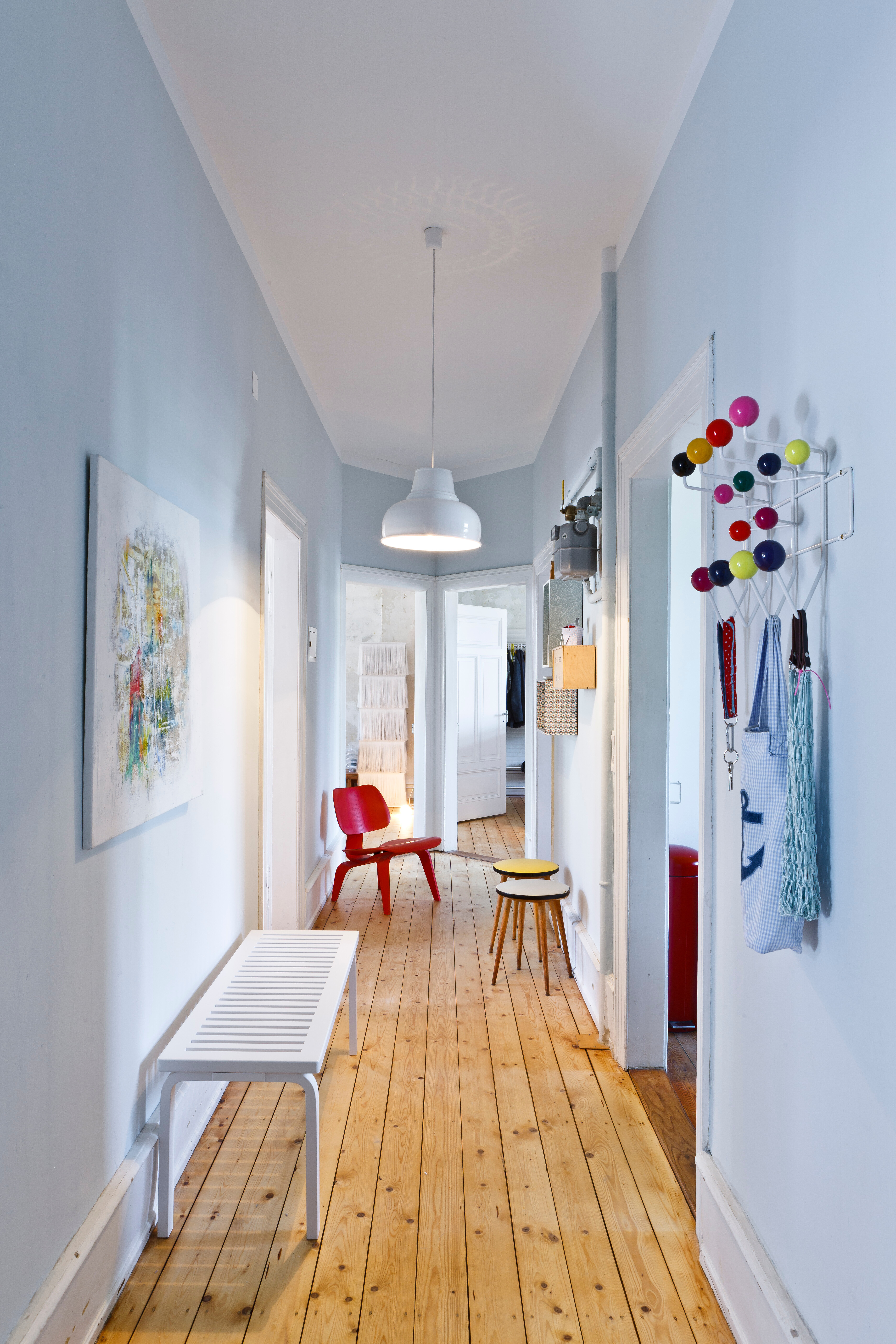 Die Bank Bench 153 von Alvar Aalto, der Plywood Chair und die Garderobe Hang it all, beides von Vitra, sorgen für einen gelungenen Empfang der Gäste. Design: Charles und Ray Eames