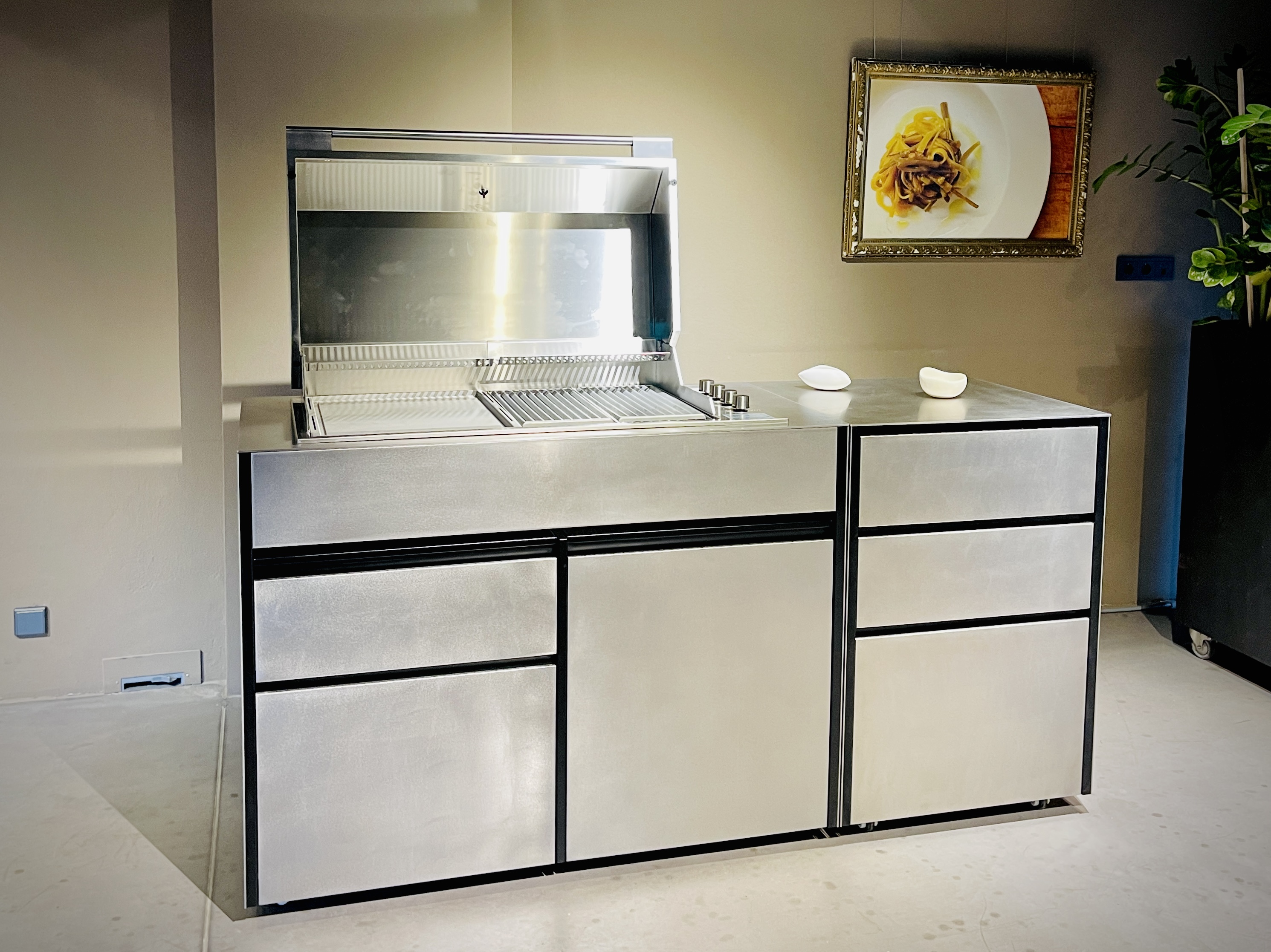 Offene Edelstahl-Außenküche von JOKODOMUS mit Grillmodul in Innenraumszenerie