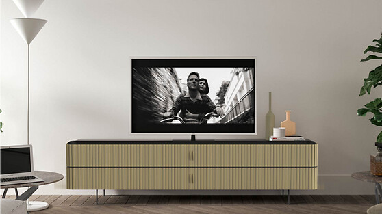 TV-Möbel mit hellem Lamellenkorpus und dunkler Deckplatte auf dunklem Holzfußboden