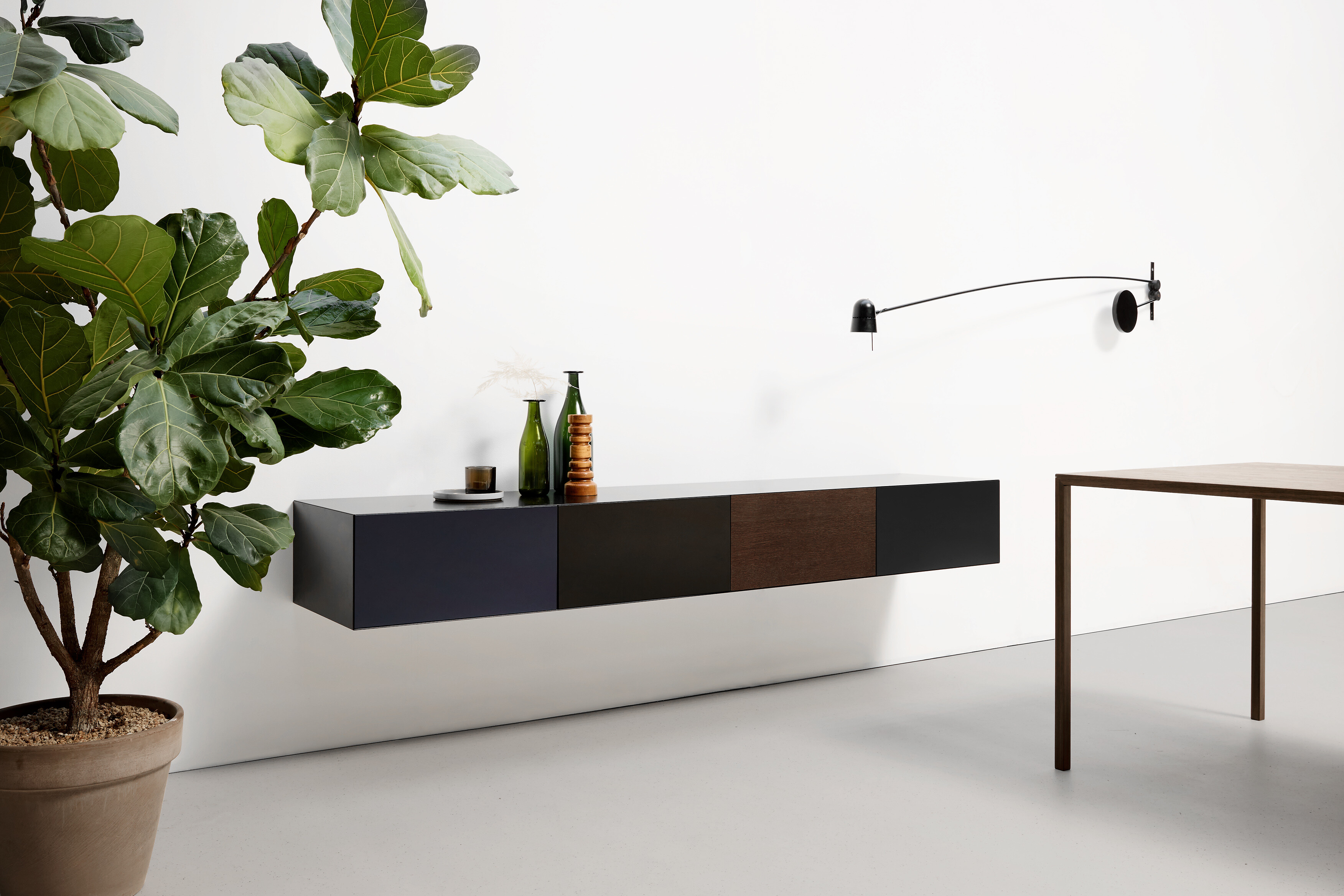 Wandhängendes Sideboard mit abgesetzten Fronten in Schwarz und Holz vor weißer Wand