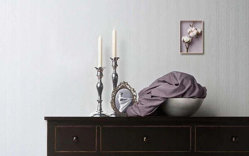 Dunkle Kommode mit Kerzenständern, gerahmtem Bild und Stoff in Schale arrangiert