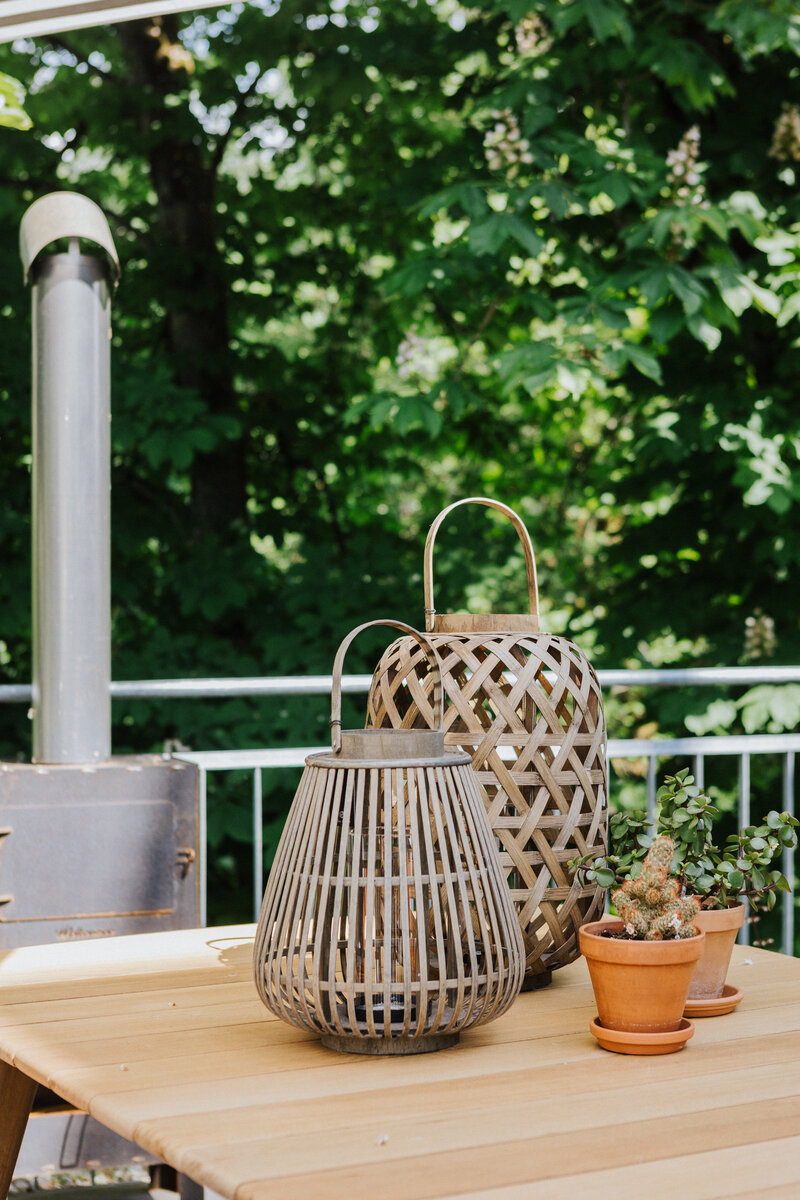 Zwei geflochtene Laternen und kleine Terrakotta-Pflanztöpfe auf einem Holztisch in der Ausstellung Waldshut bei Seipp Wohnen