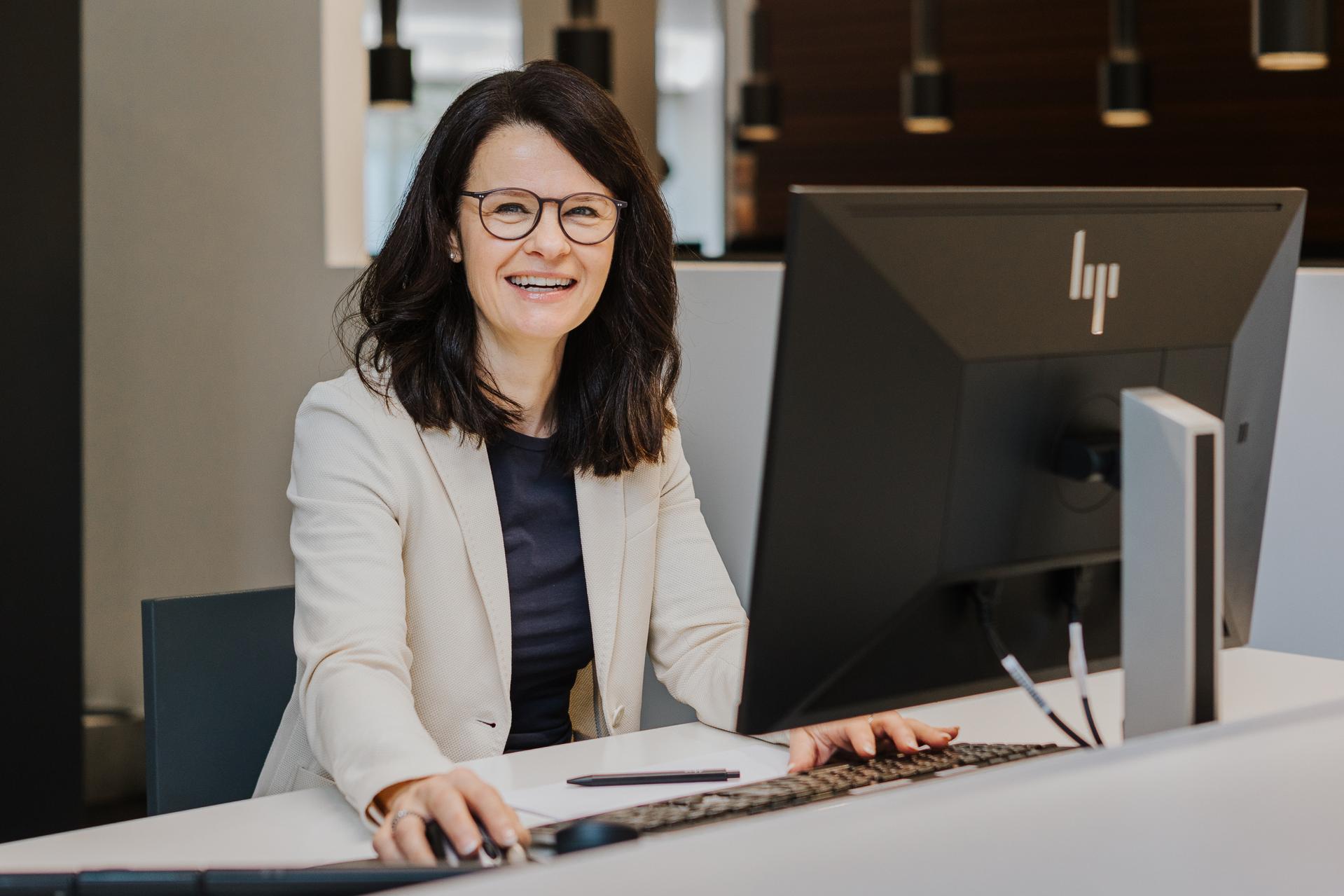 Service-Mitarbeiterin bei Seipp Wohnen in Tiengen am Empfang mit Computer und freundlichem Lächeln.