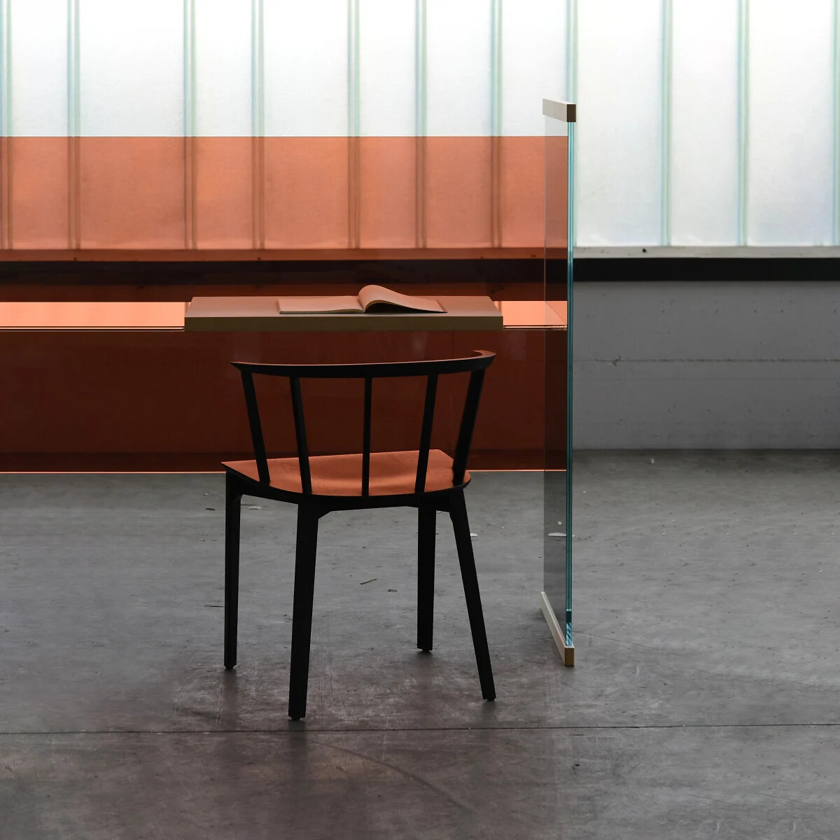 Glasschreibtisch in Kombination mit Stuhl vor transluzenter Wandstruktur.