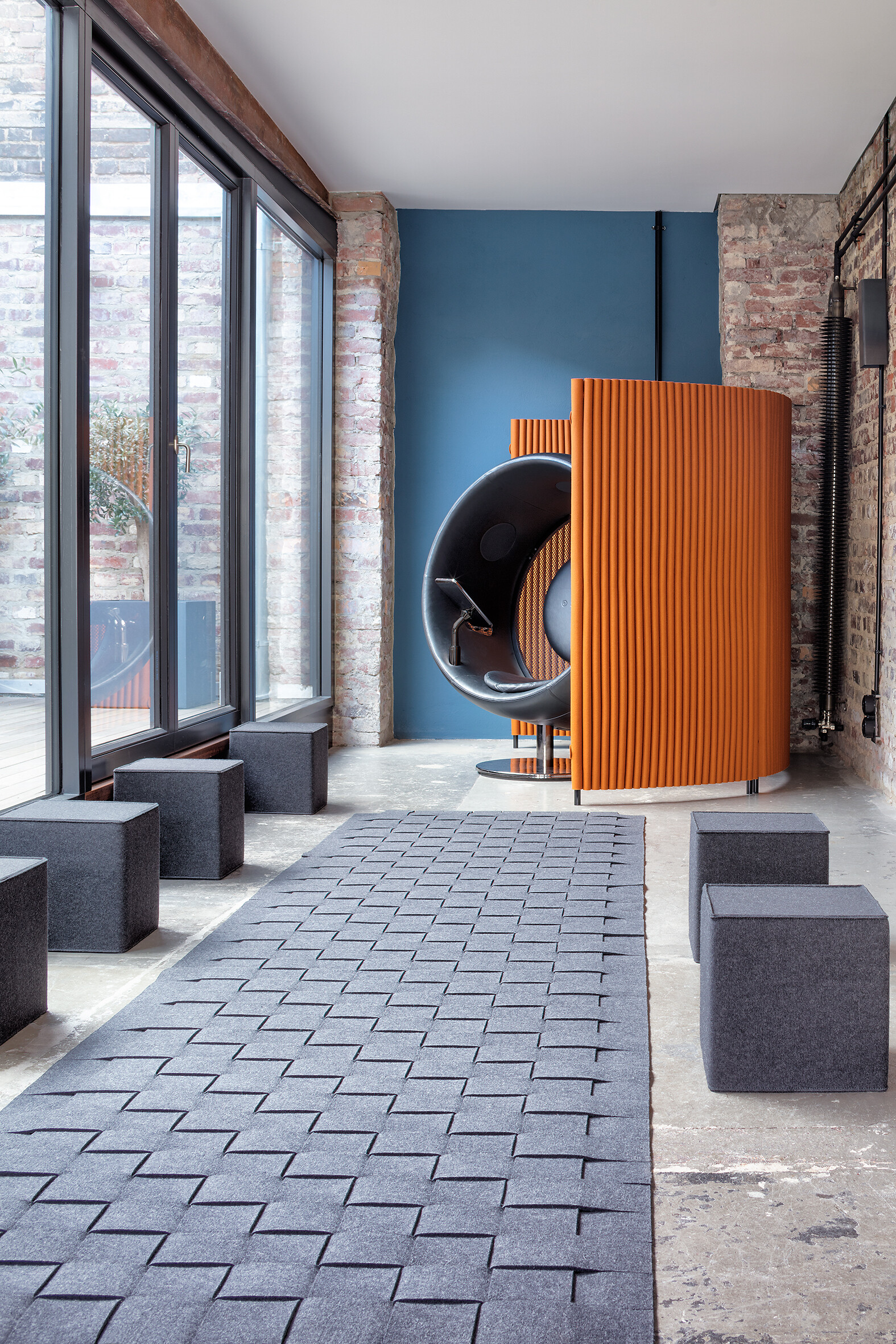 Akustikkabine mit orangefarbenem Filzpaneel und Würfelsitzen aus Filz