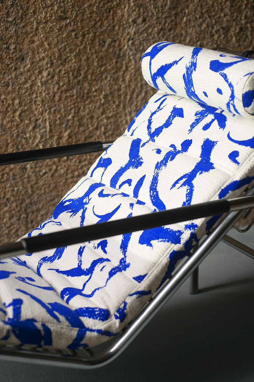 Liegesessel mit grafisch gemustertem Bezug in Blau auf Weiß, Stoff von Dedar vor Wandfläche