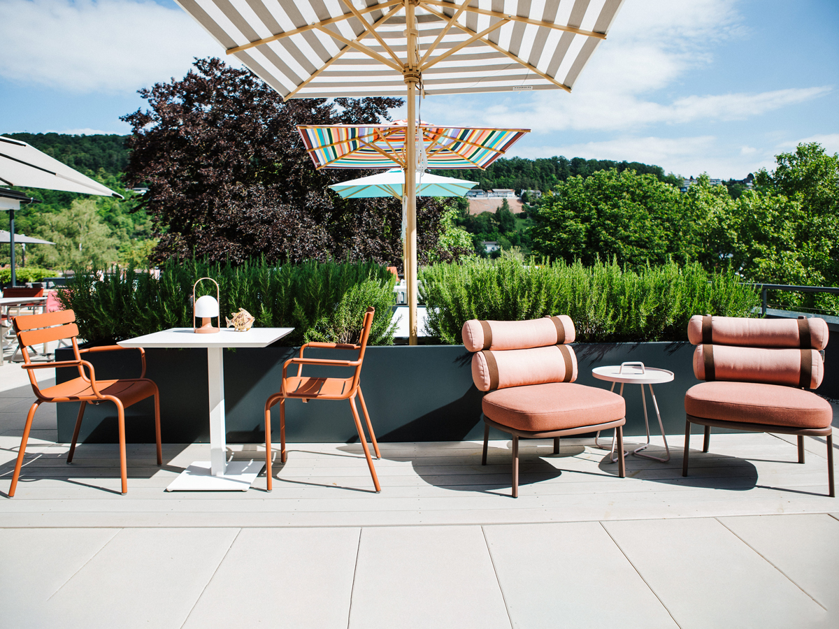 Outdoor-Ausstellungsfläche von Seipp Wohnen in Tiengen mit farbenfrohen Gartenmöbeln, Sonnenschirmen und viel Grün.