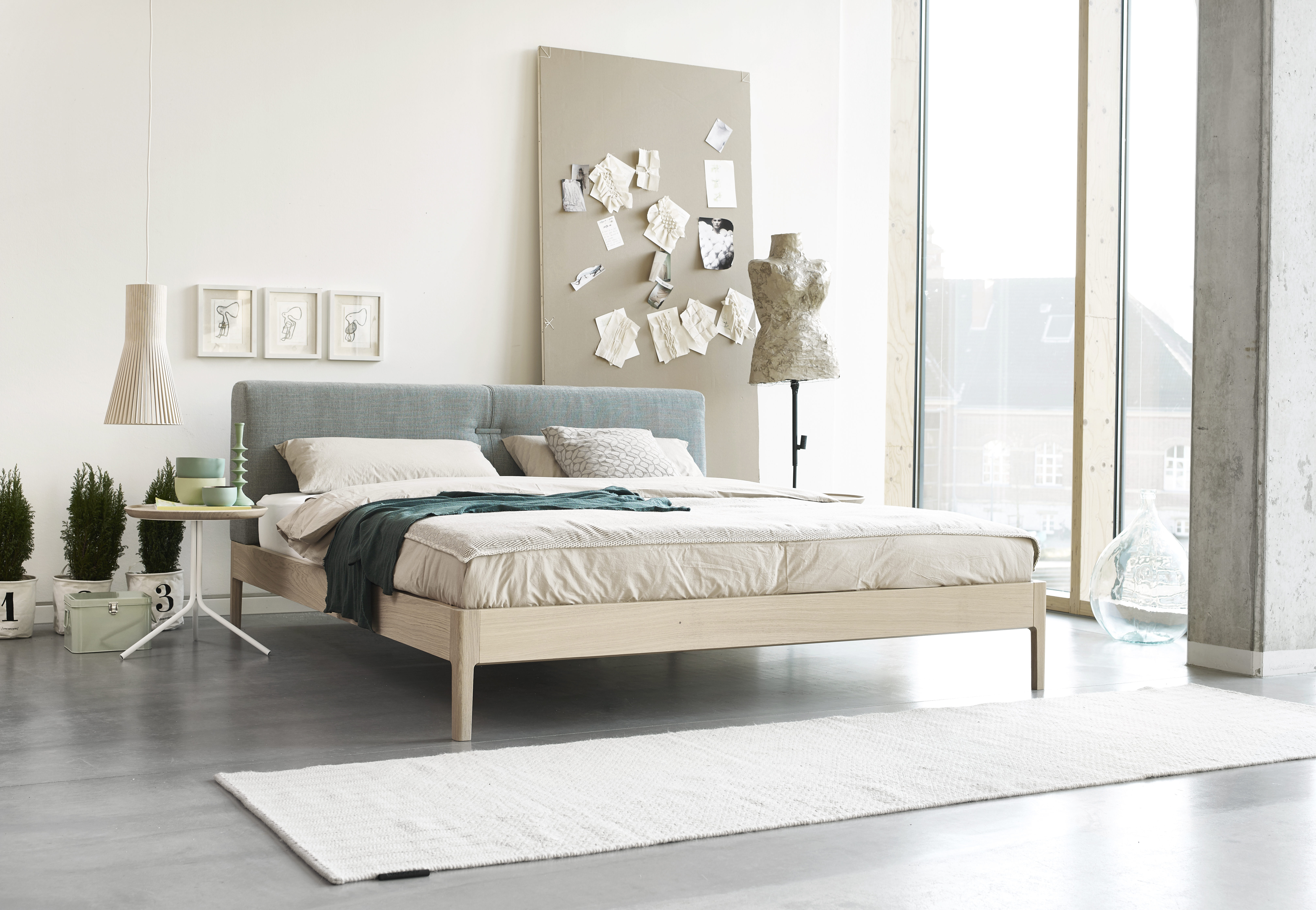 Bett mit hellblauem Stoffkopfteil und hellem Holzrahmen in modernem Schlafzimmer