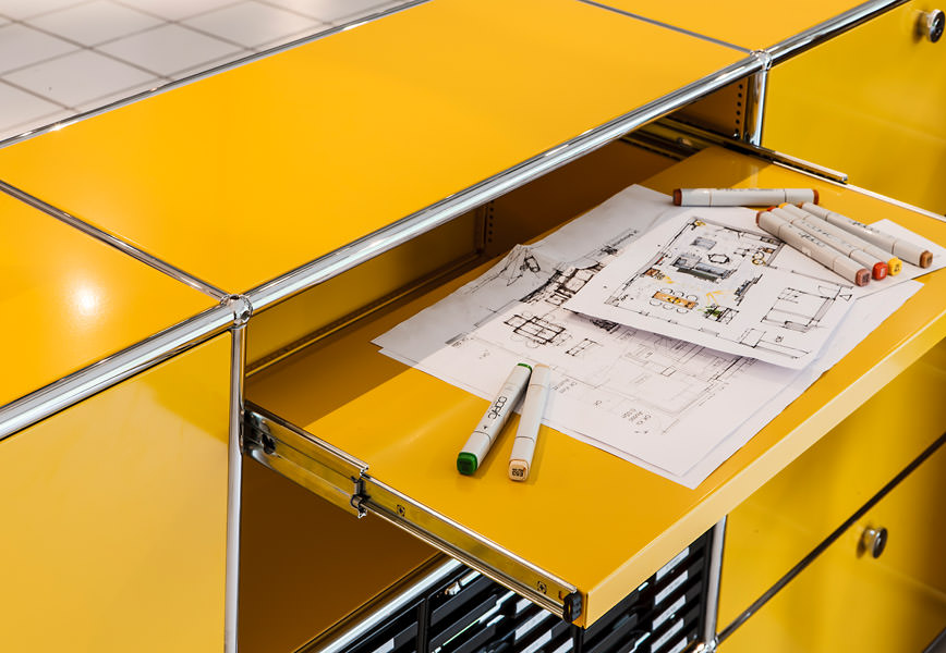 Geöffneter gelber USM Haller Auszug mit Architekturplänen und Markern – Planungsumfeld bei Seipp Wohnen, sinnbildlich für Beratung und Raumkonzepte.