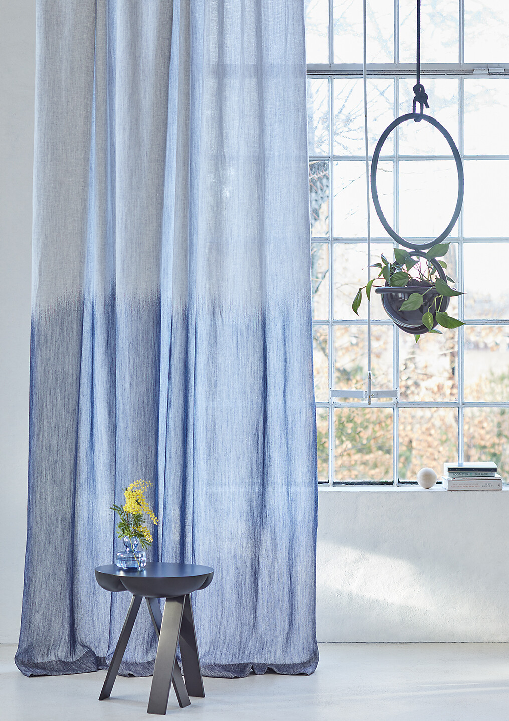Vorhangstoff mit Verlauf von Weiß zu Blau vor großem Sprossenfenster inszeniert