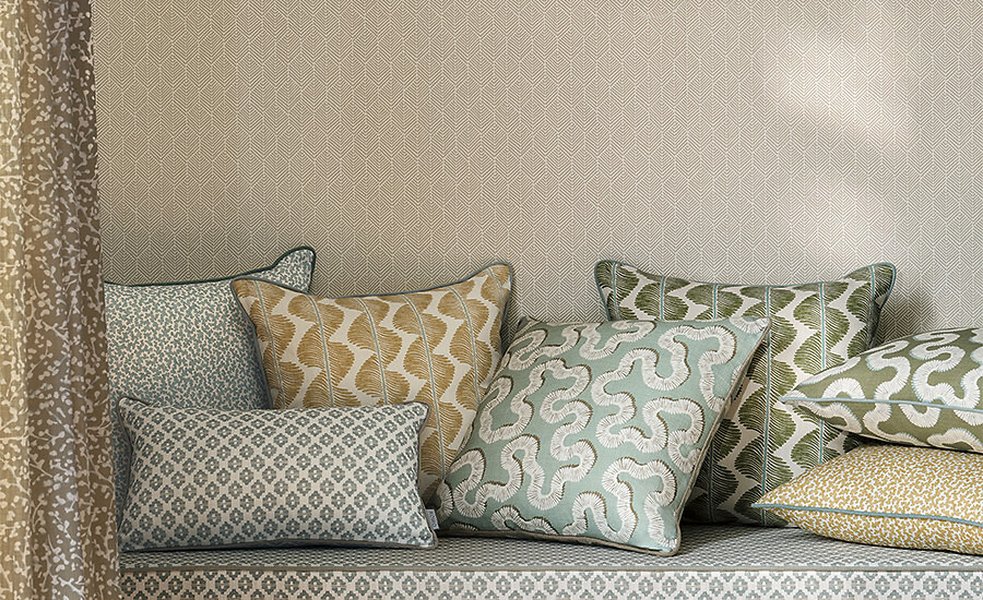 Mehrere Zierkissen in geometrischen Mustern und Pastelltönen auf heller Polsterbank