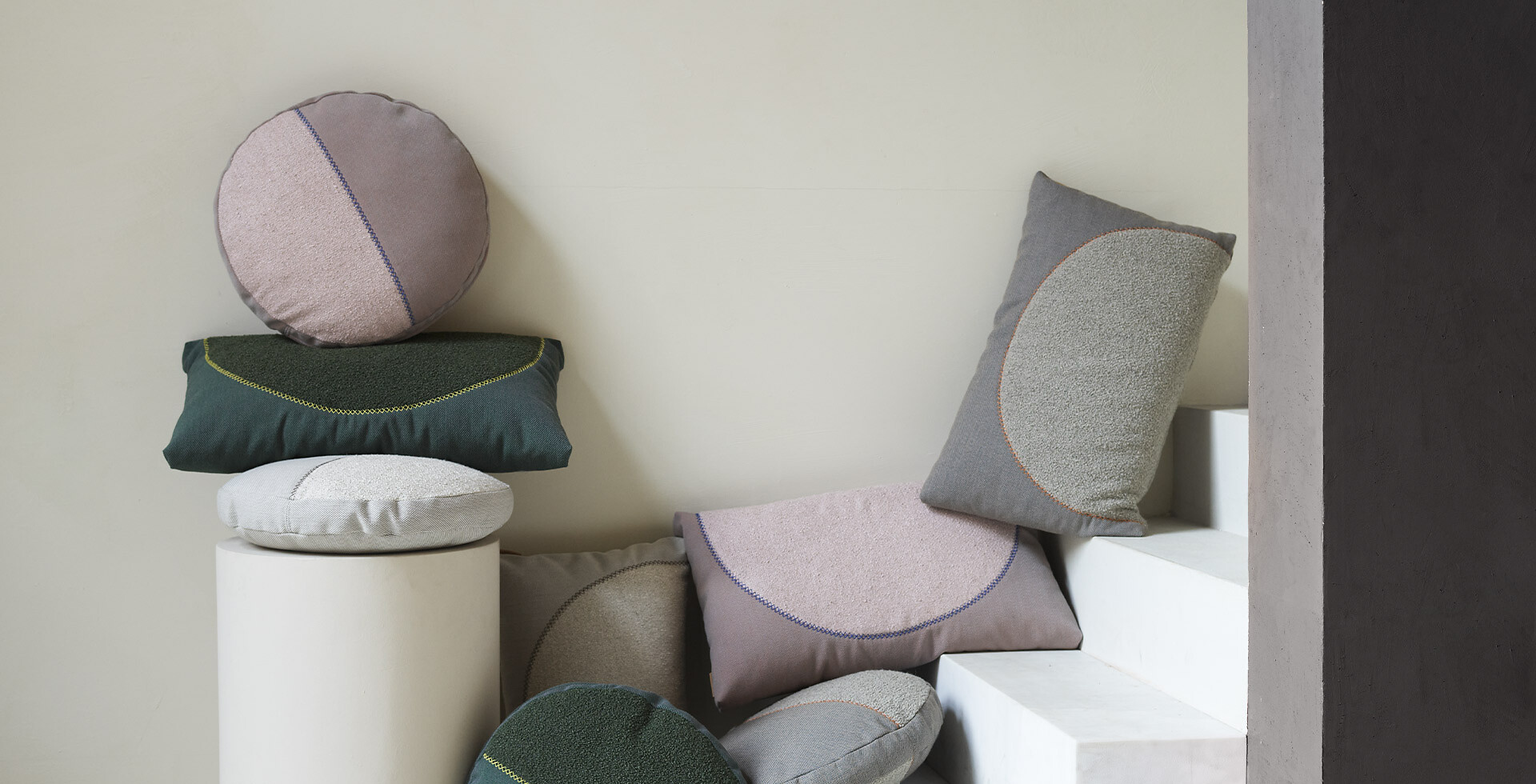 Dekorative Kissen in unterschiedlichen Farben und Formen, locker gestapelt und an Wand gelehnt