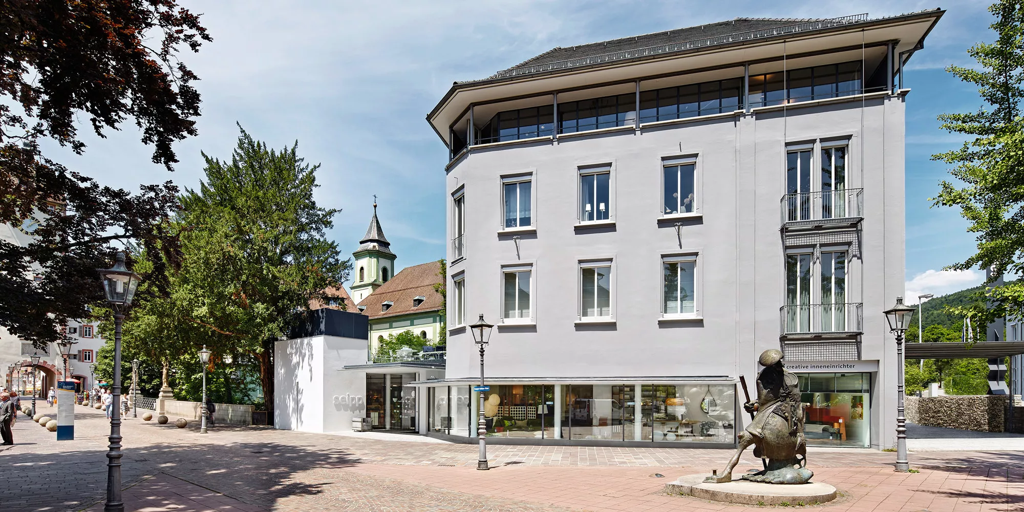 Seipp Wohnen in Waldshut mit klassizistischer Fassade und Schaufensterfront, Bronzefigur im Vordergrund