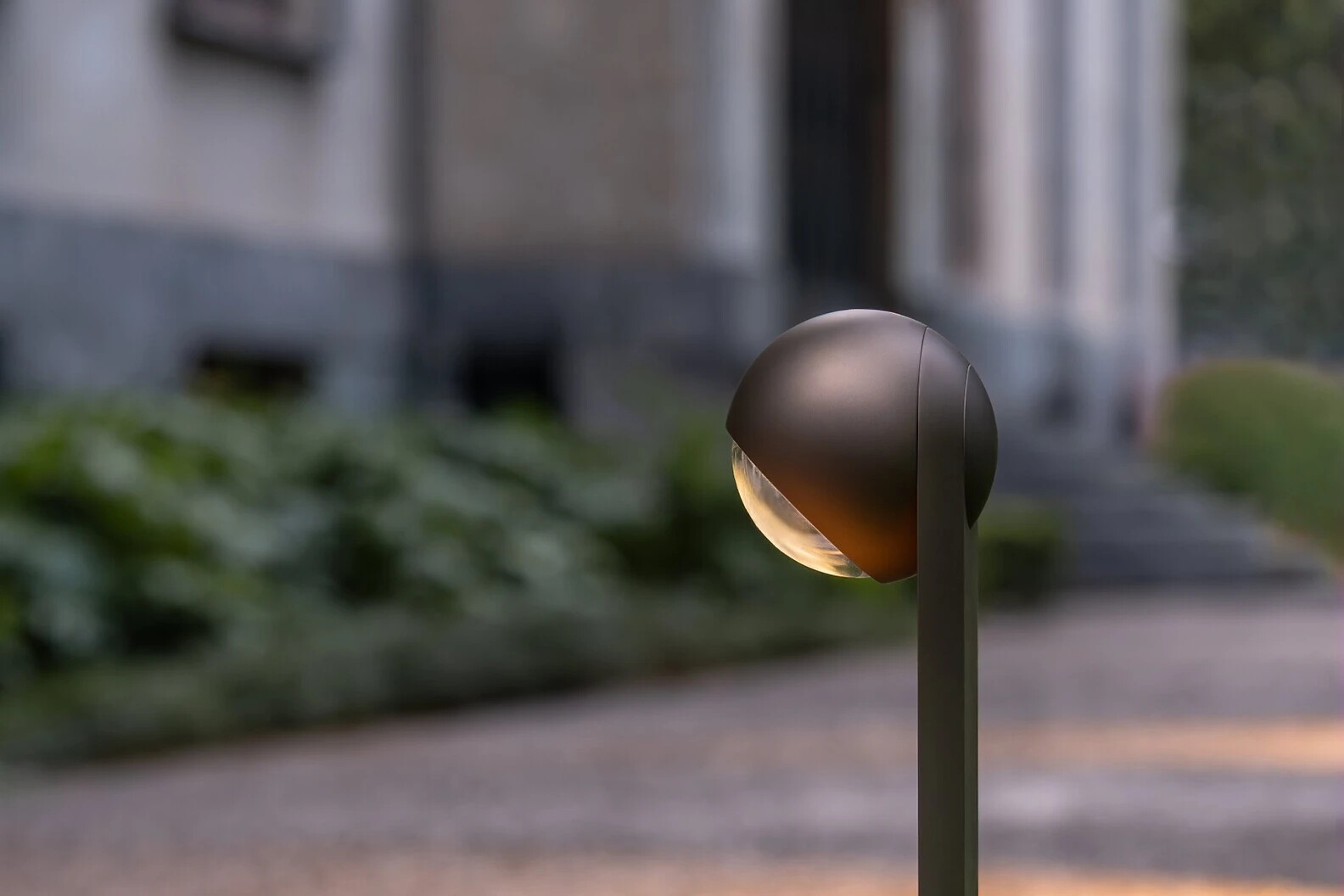 Außenleuchte Sito palo von Occhio neben Weg in Gartenanlage mit architektonischer Fassade