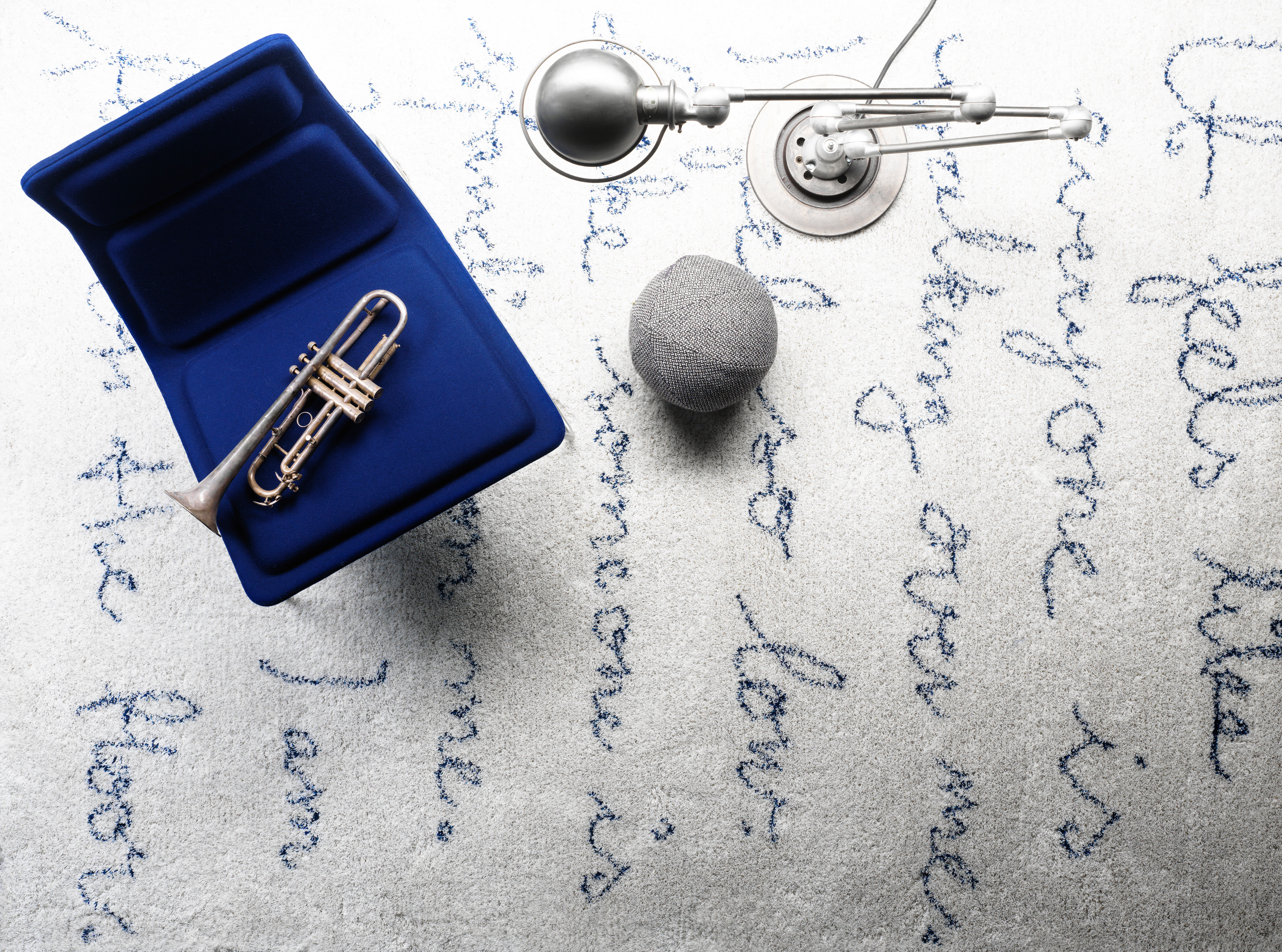 Heller Kasthall-Teppich mit handgeschriebener Textstruktur und Sitzobjekten in Grau