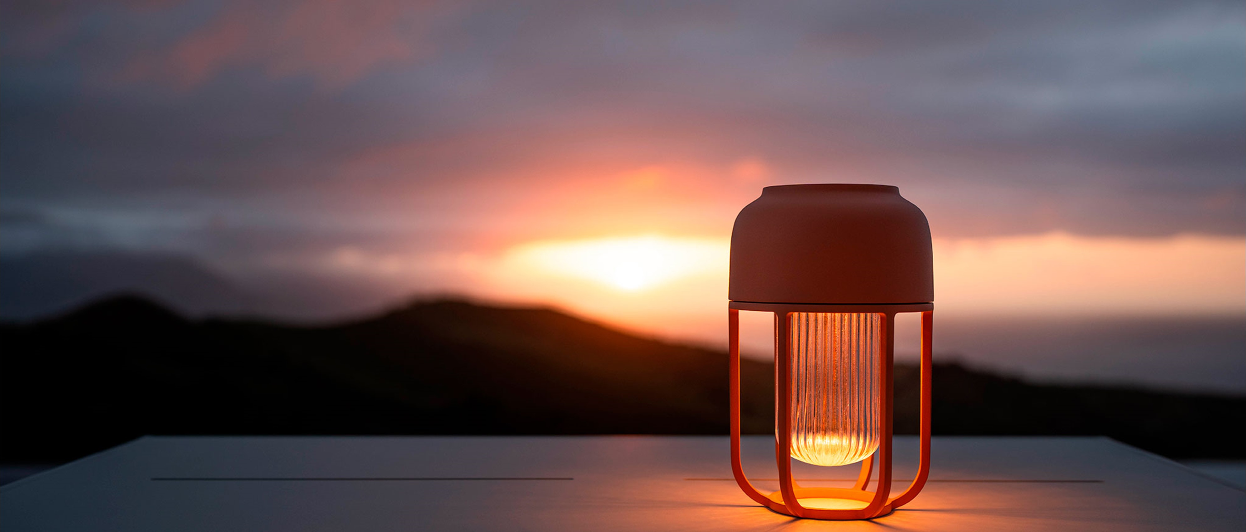 Solarleuchte Light No1 von Houe im Abendlicht mit Blick auf dunkle Hügelkette und Sonnenuntergang.