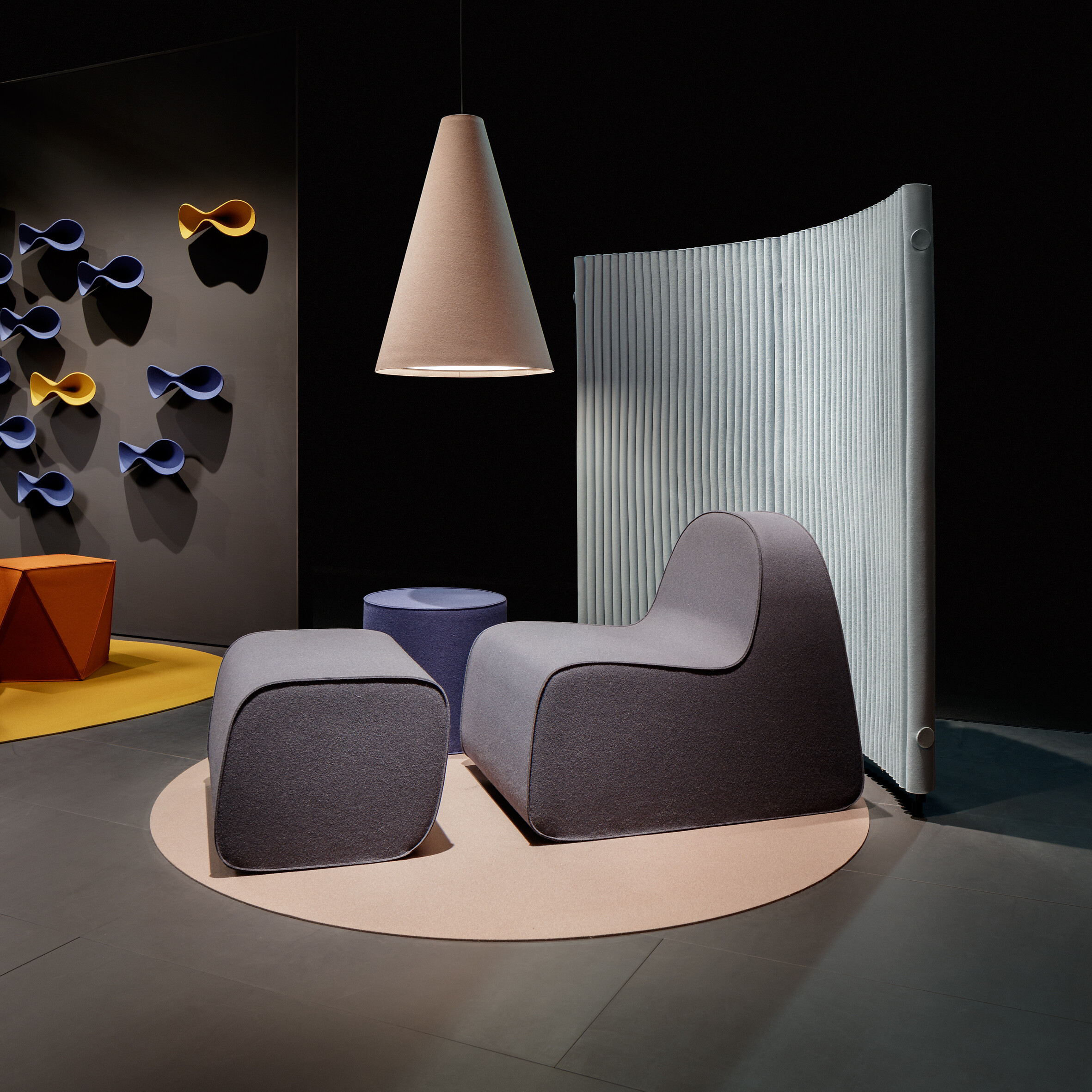 Sitzgruppe mit hellgrauem Lounge-Sessel, Raumtrenner und Leuchte aus Filz