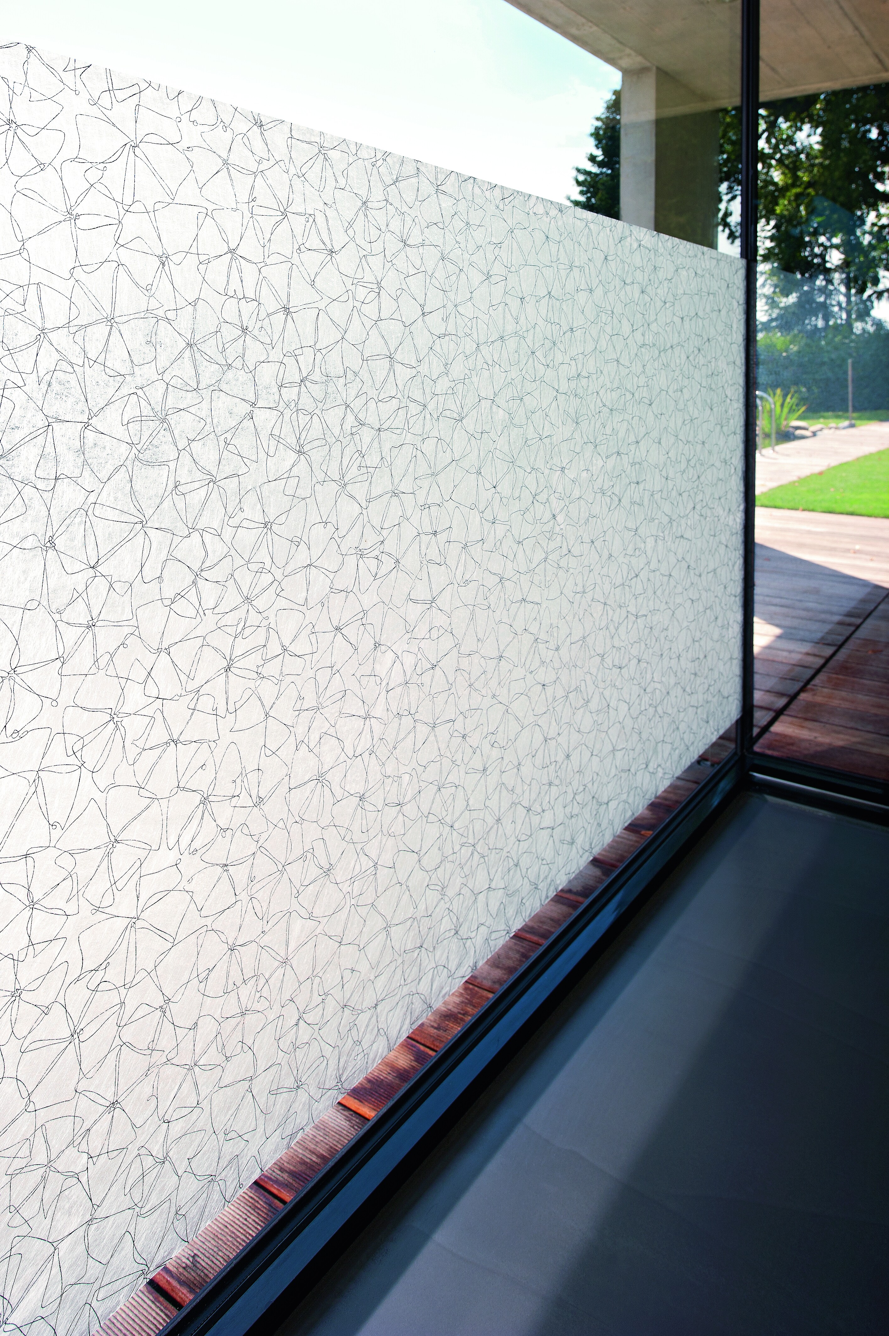 Teilflächig beklebte Glasfront mit lichtdurchlässiger Fensterfolie im filigranen Linienmuster