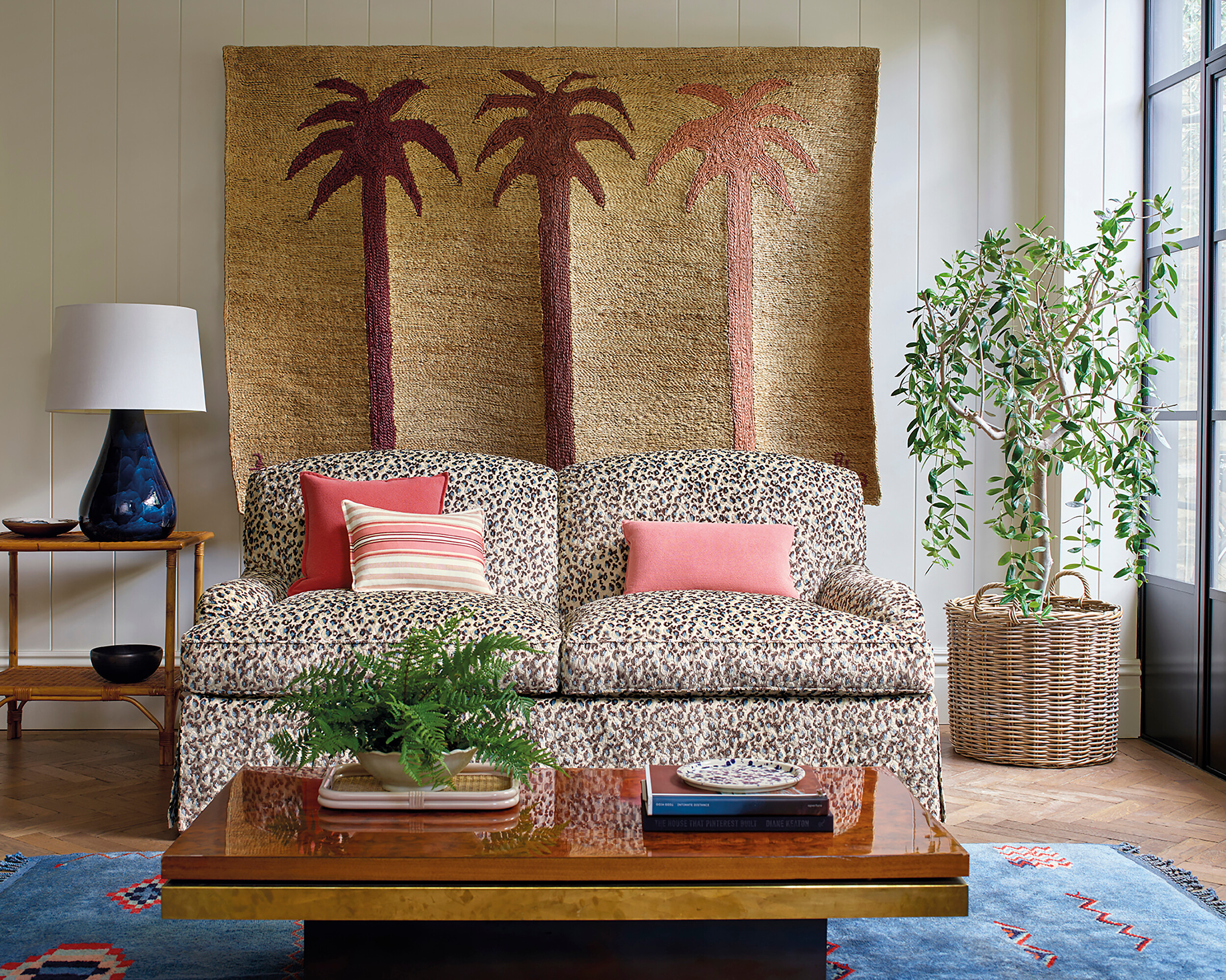 Zweisitzer mit Animal-Print vor Wandbehang mit Palmenmotiv in warmen Naturtönen