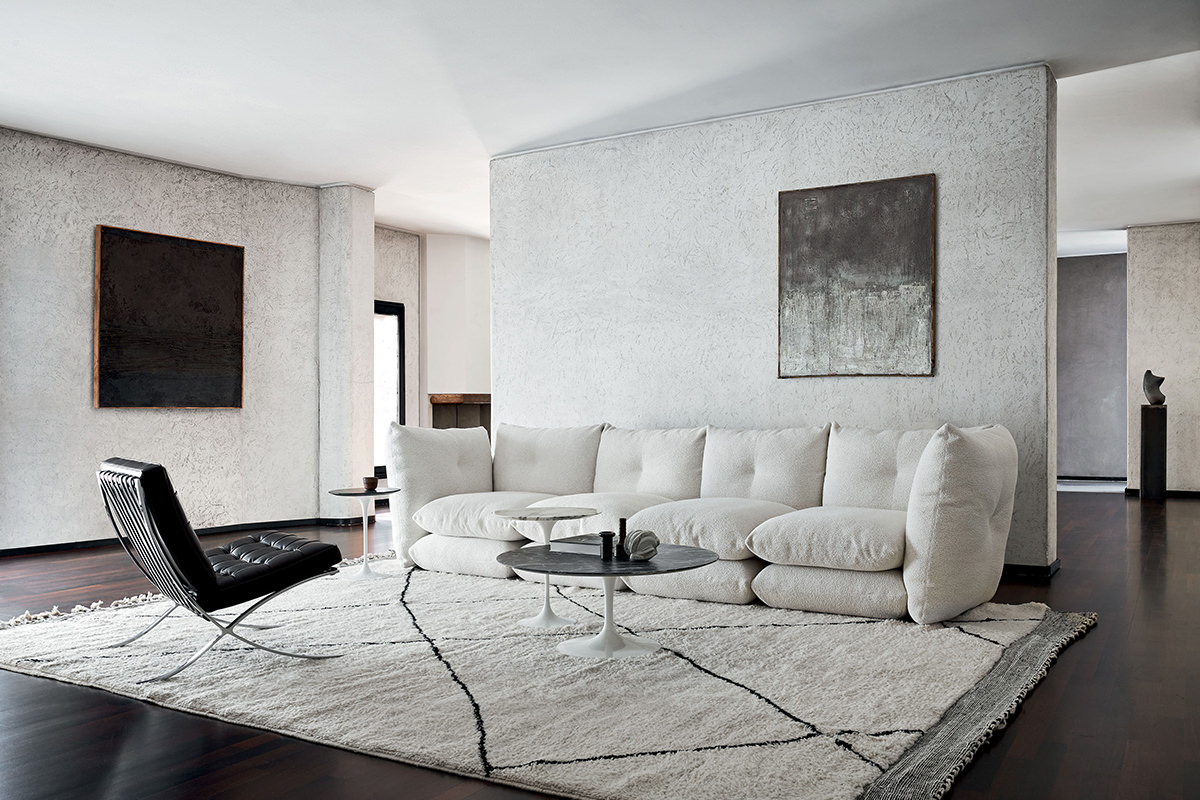 Ein Wohnzimmer mit dem großzügigen Perron Pillo Sofa und dem ikonischen Barcelona Chair von Knoll. Saarinen Tische runden das stilvolle Ensemble harmonisch ab.
