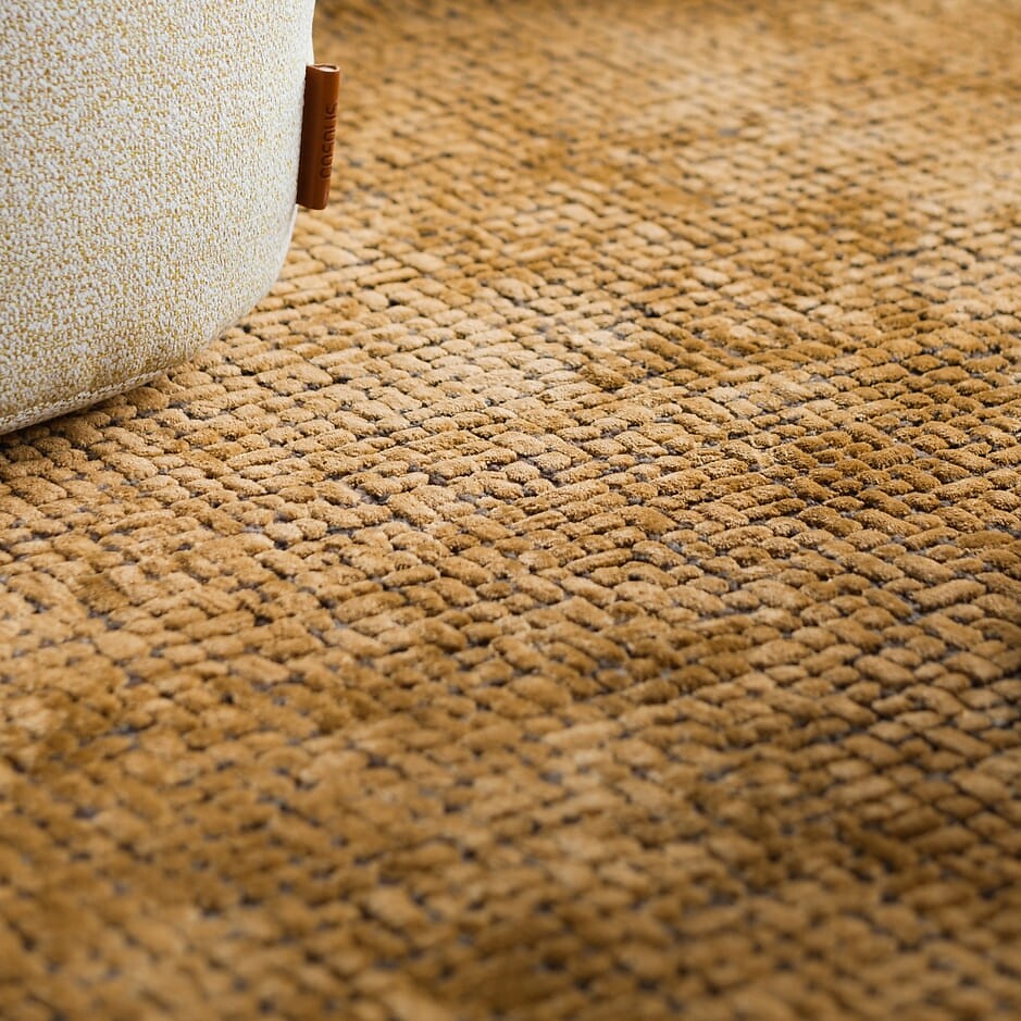 Nahaufnahme eines strukturierten, senfgelben Teppichs mit weicher Haptik